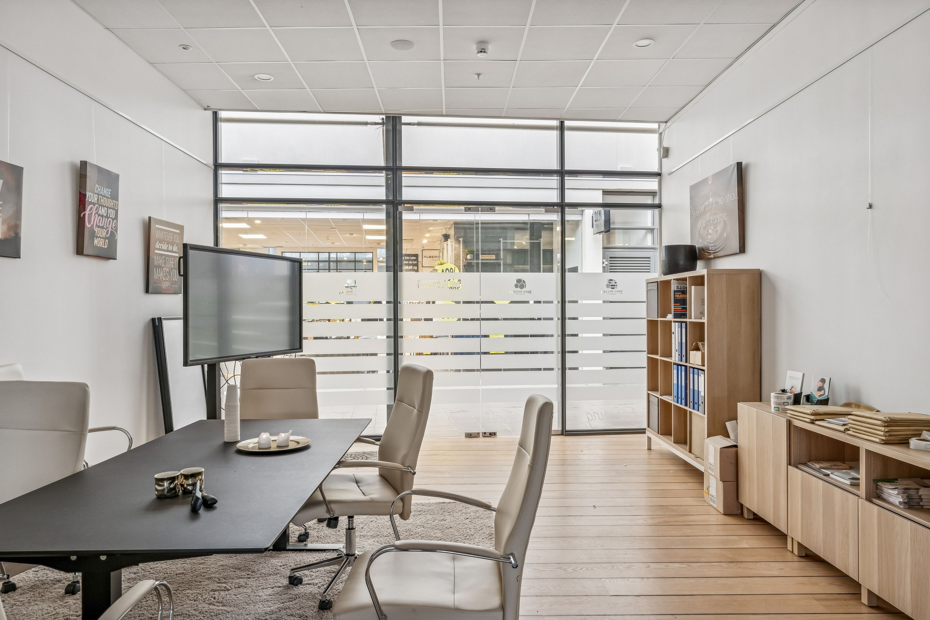 Et velindrettet kontor med hvide vægge, lyse trægulve og moderne møbler samt en stor vinduesfront til Bagsværd Hovedgade 126D.