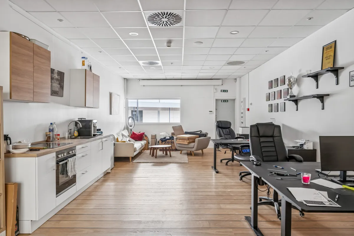 Foto af lukket, velindrettet og moderne kontor med møbler, bord, stol, computer, skrivebord, kogeapparat og loft.