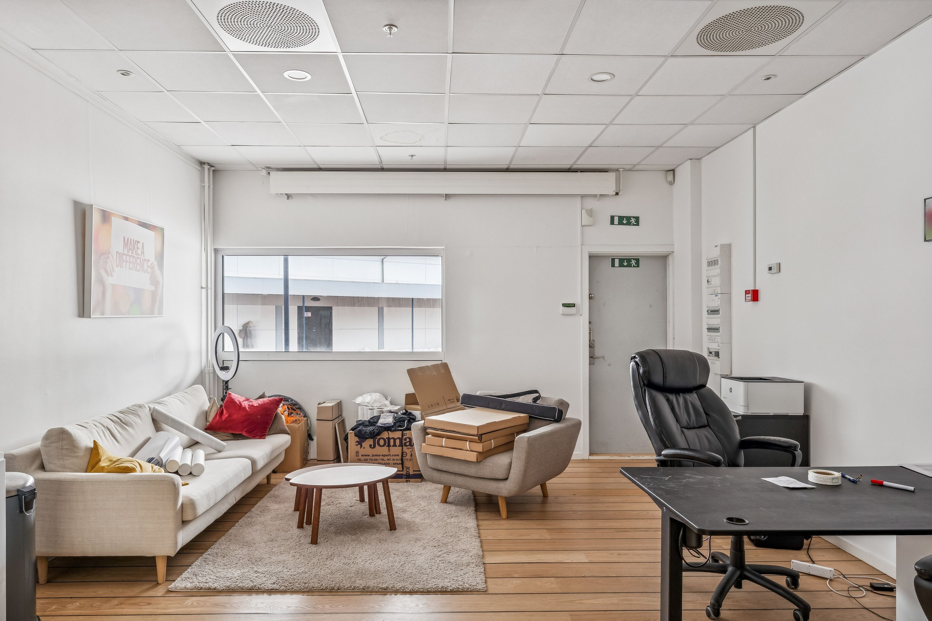 Inde i en butik med en stor sofa, to stole, et skrivebord og et vindue med udsigt til Bagsværd Centret.