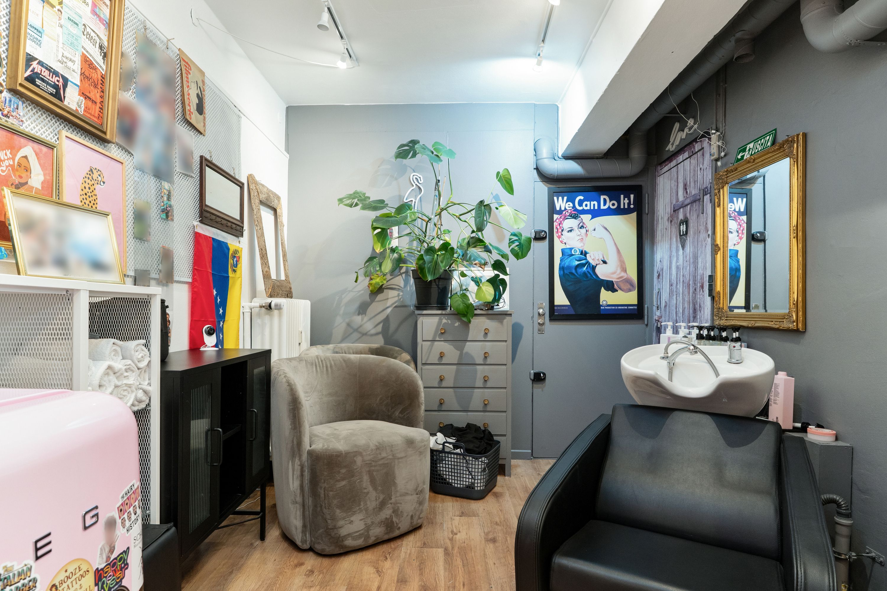 En skøn interiør med plante, to stole, et hårklippestol, et spejl og en håndvask med toiletartikler.
