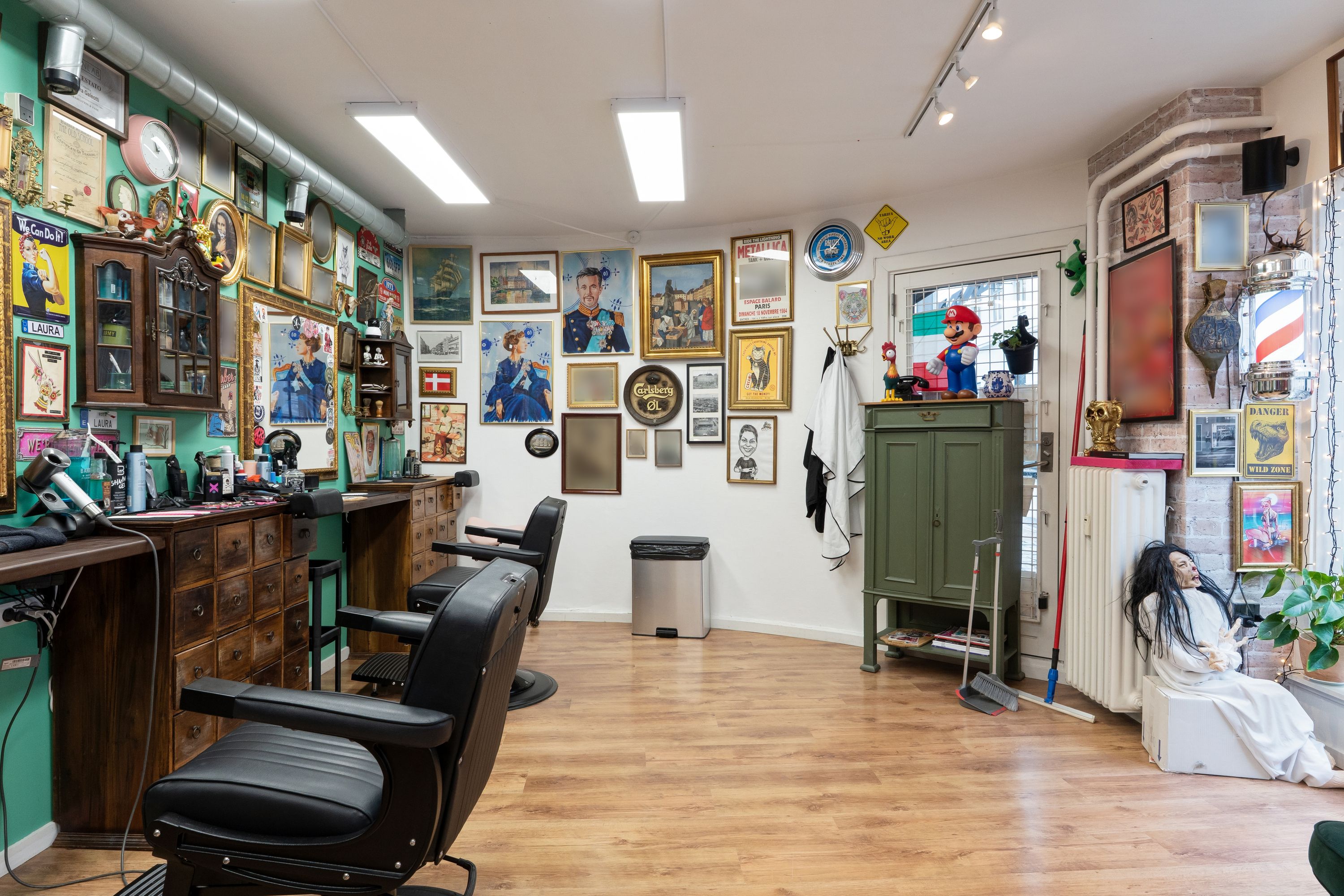 Barberforretning med barberstole, tørhår og udstyr samt en række udsmykninger på væggene som klokker, malerier og skilte