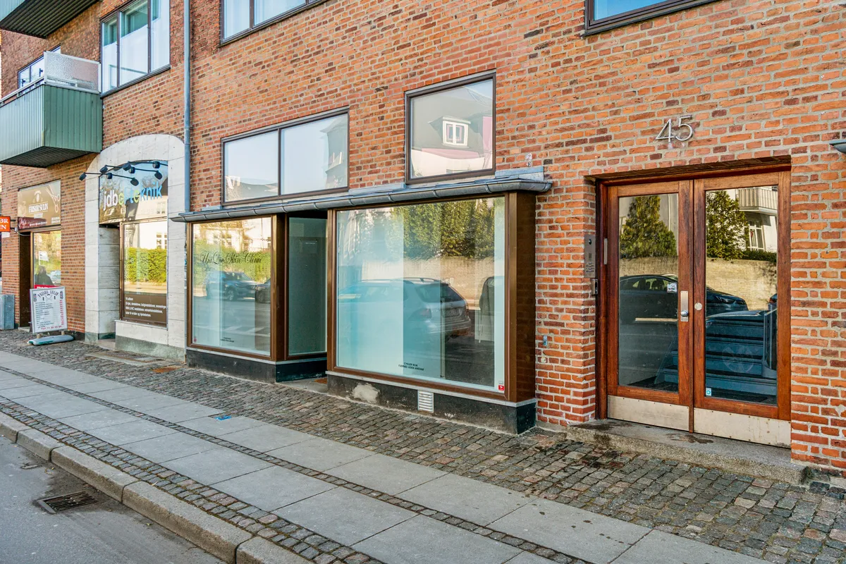 Butikstil leje på Søndre Fasanvej 45. Bygningen har røde mursten og store glasvinduer. På facaden står nummer 45. Der er en åben indgang og udsat skilt