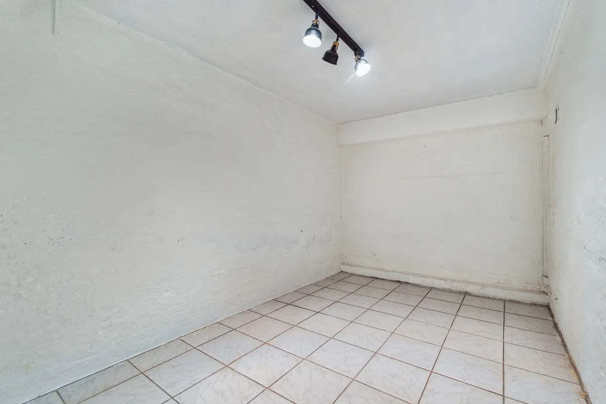 En stor, lysegrå, ubenyttet butikslokale med smukke gulvfliser og tre hængelys på loftet. Lokalet ligger på Søndre Fasanvej 45, st. 2, Frederiksberg.