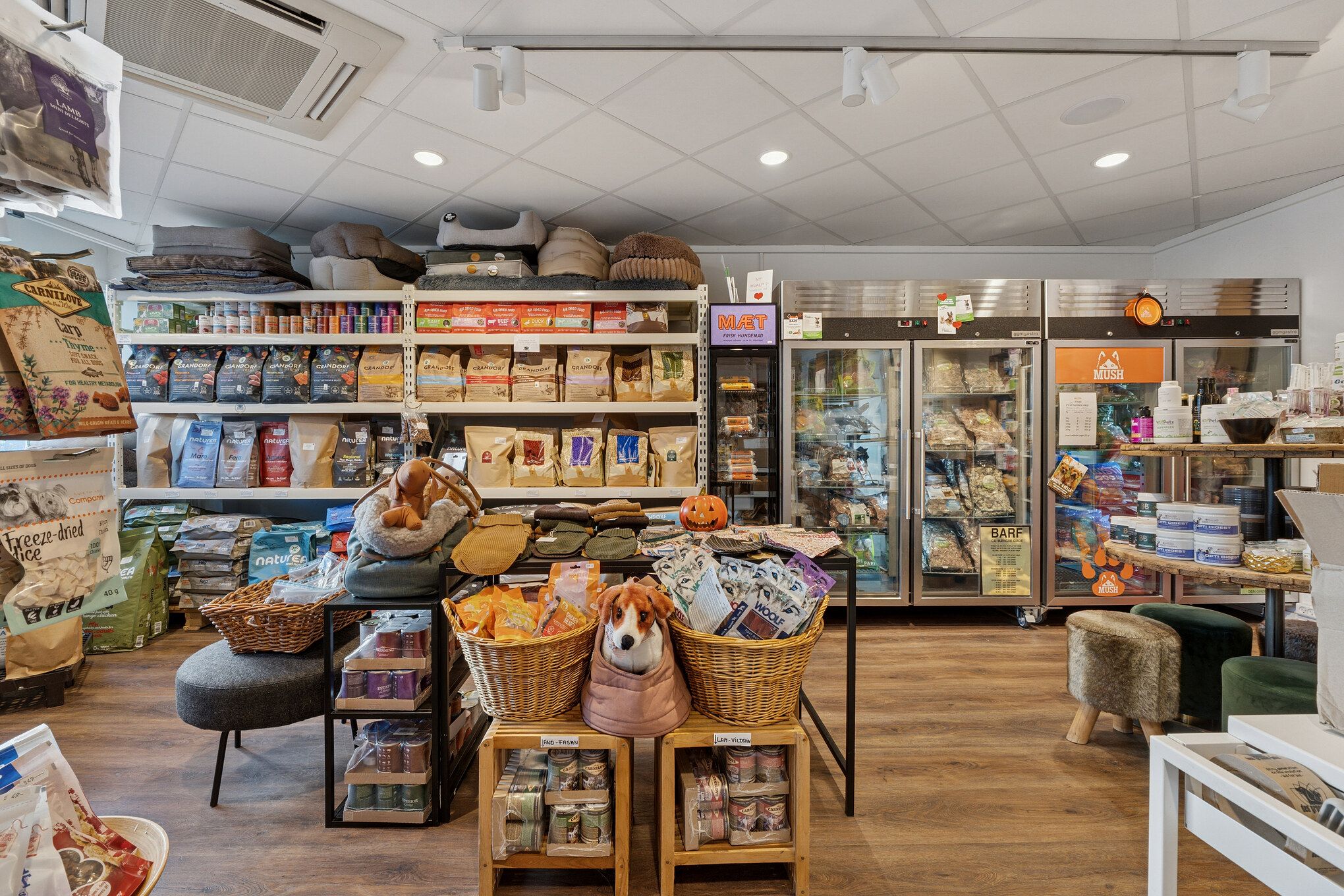 Kæledyrsbutik med produkter i kurve og skabe samt toppe og tæpper på hylder og loft