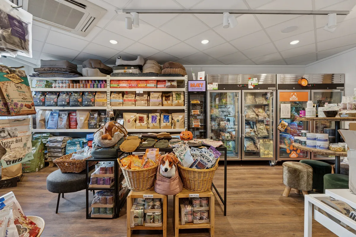 Kæledyrsbutik med produkter i kurve og skabe samt toppe og tæpper på hylder og loft