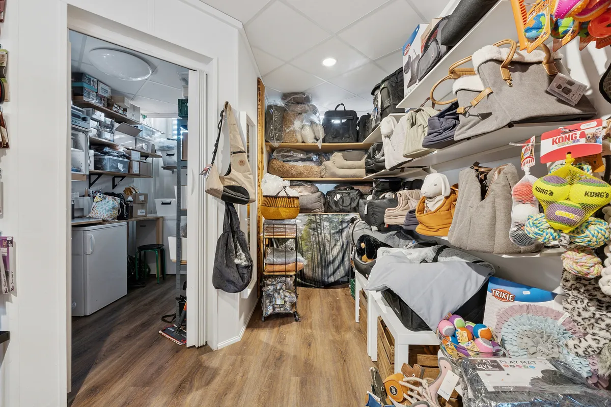 Menighedslokaler med trægulv og moderne indretning til leje i Charlottenlund. Butikken har flere hylder med varer og produkter samt flere opbevaringsbokse på væggen