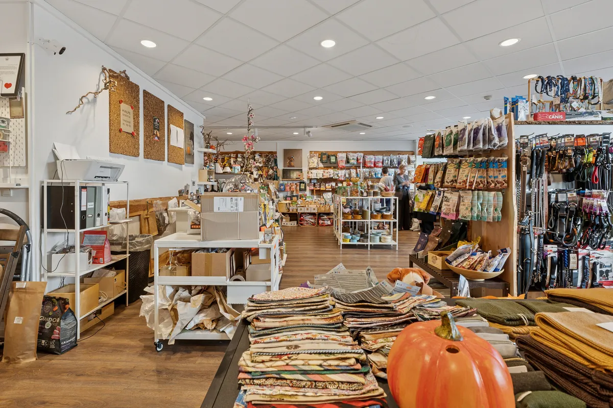 Lyst og indbydende butikslejemål med tekstiler, pumser, hundemad og hundetilbehør i en bred og flot facade med to store vinduer i Charlottenlund