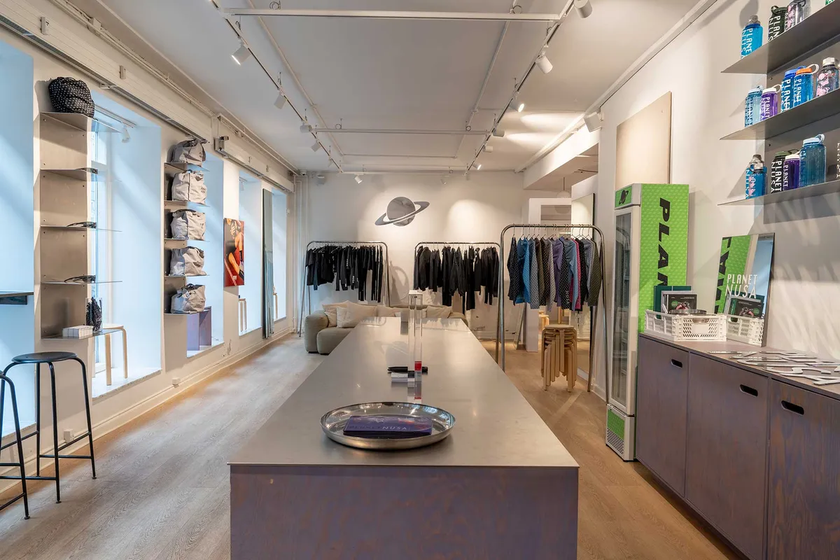 Lys og rummelig butik med salgspuljer og sofaer i Latinerkvarteret. Flad loft og gulv med lysepunkter og produkter på hylder.