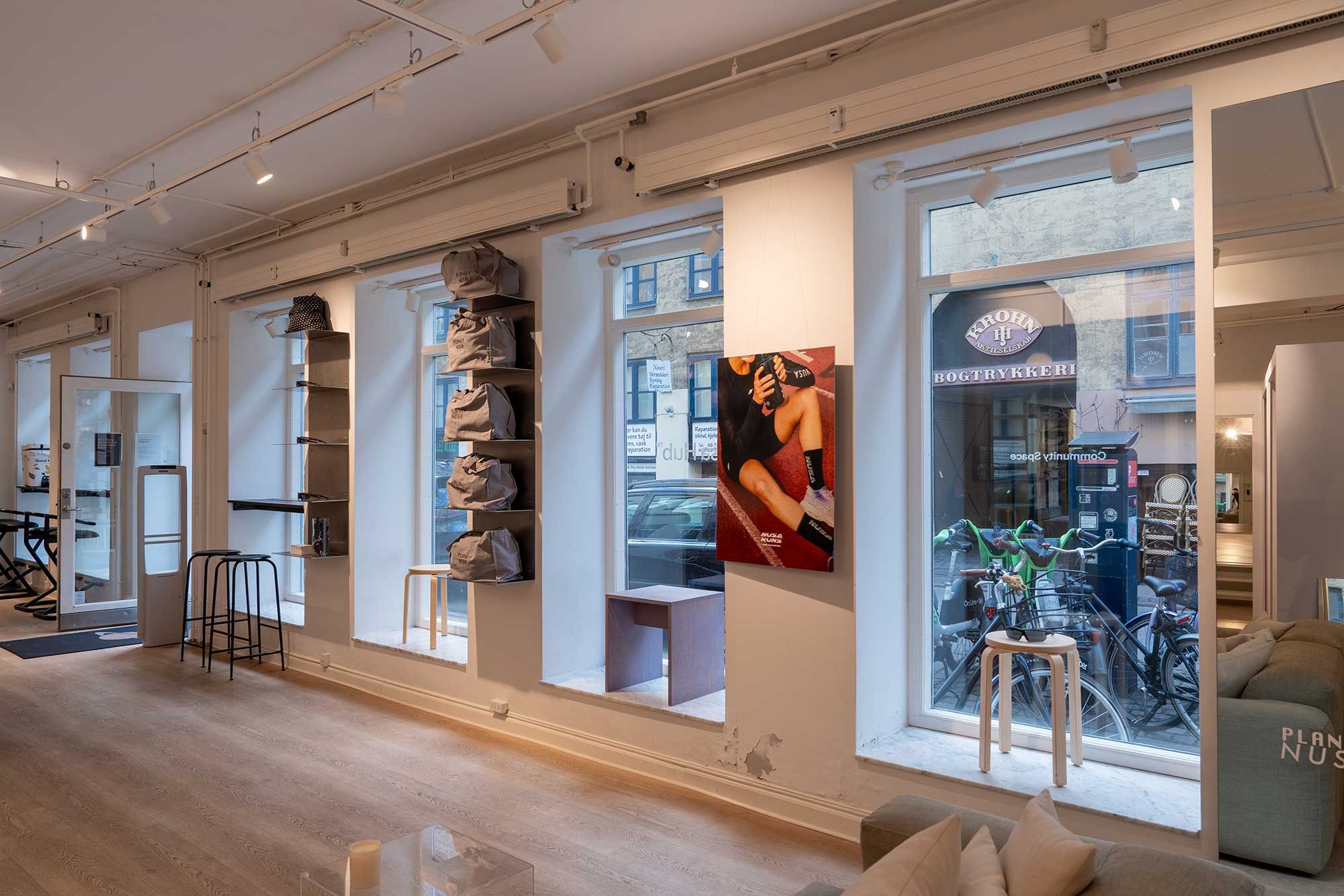 Markant butikslejemål med stort vindue og møbler i Latinerkvarteret, køkken og loftsrum til leje, hyggeligt møbleret interiør med lyse farver og moderne design.