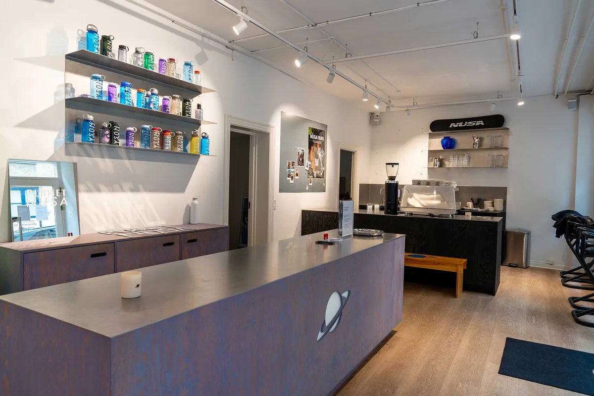 Markant lejemål med stort salgsområde og moderne design. Butik med eksponeret plakat og salgsregnskaper. Udstil produkter på høje hylder og køkken med kaffemaskine.