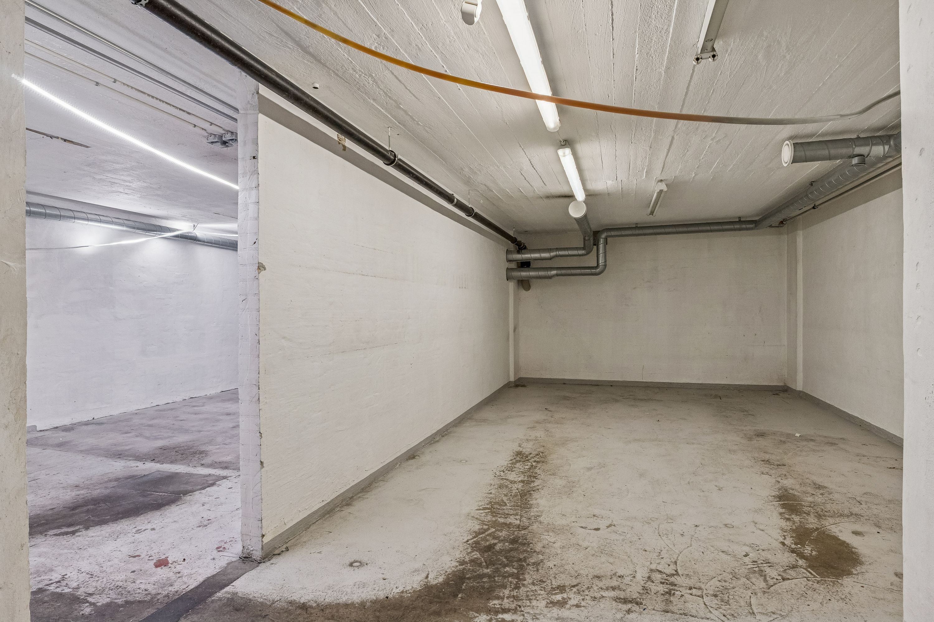 Stort lager med højloft i Charlottenlund. Rummelige lokaler med hvide vægge og lyse gulve. Åbne lagerrum med luftkanaler og rørlægning. Mulighed for forretningslokaler.