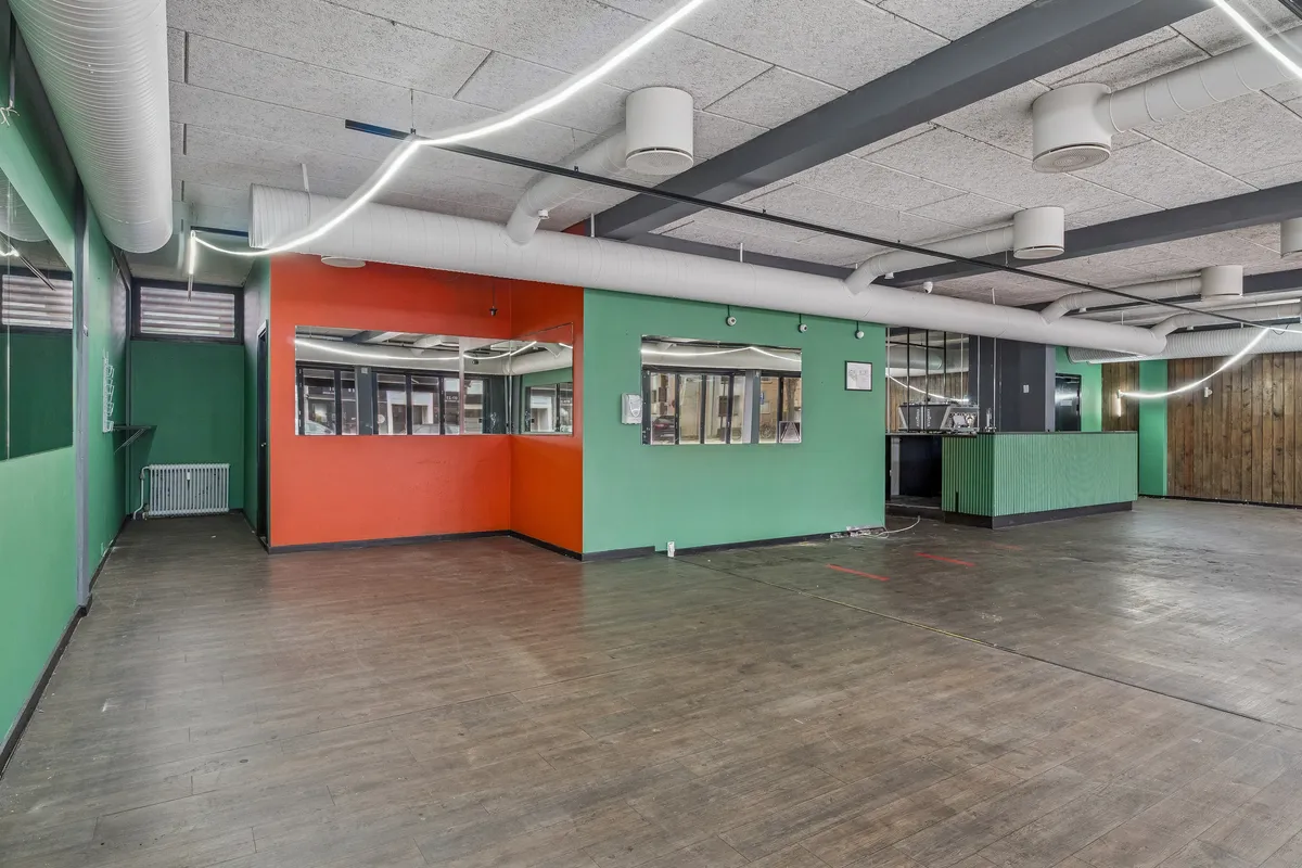 Ledig restaurantlokal til leje på Ordrupvej 57 med glasdøre og vinduer, hvidt loft, grønne og orange vægge samt træpaneler og trægulve