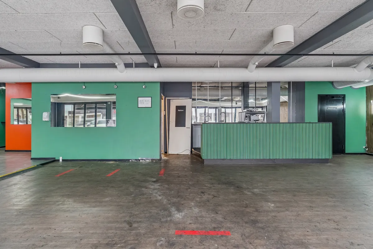 Lejlighedsrum med lysegrå loft, gulv og grøn væg. Væggen har en åbning med spejl og dør. Der er røde markeringer på gulvet.