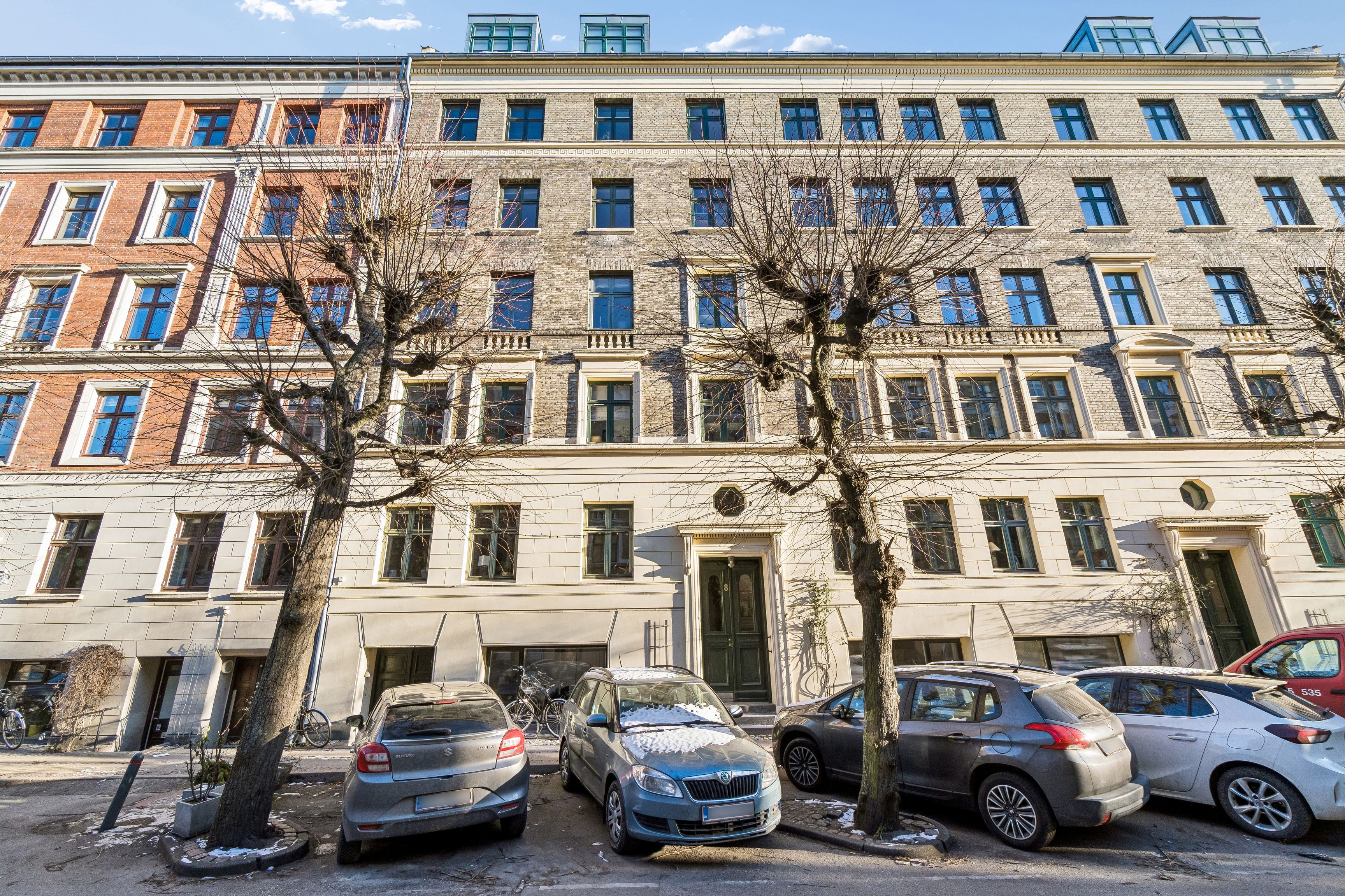 Kontor til leje på Schleppegrellsgade 8 med fem parkerede biler og to nøgne træer foran.