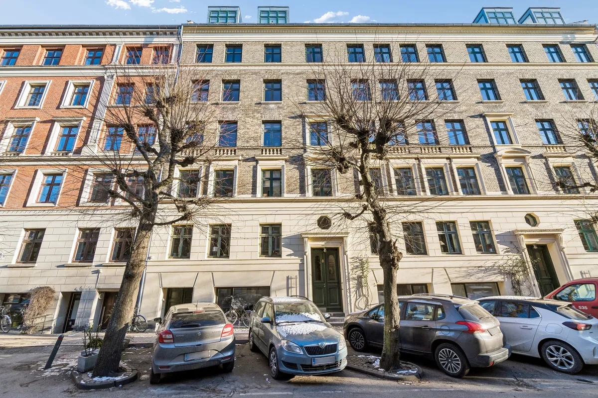 Kontor til leje på Schleppegrellsgade 8 med fem parkerede biler og to nøgne træer foran.