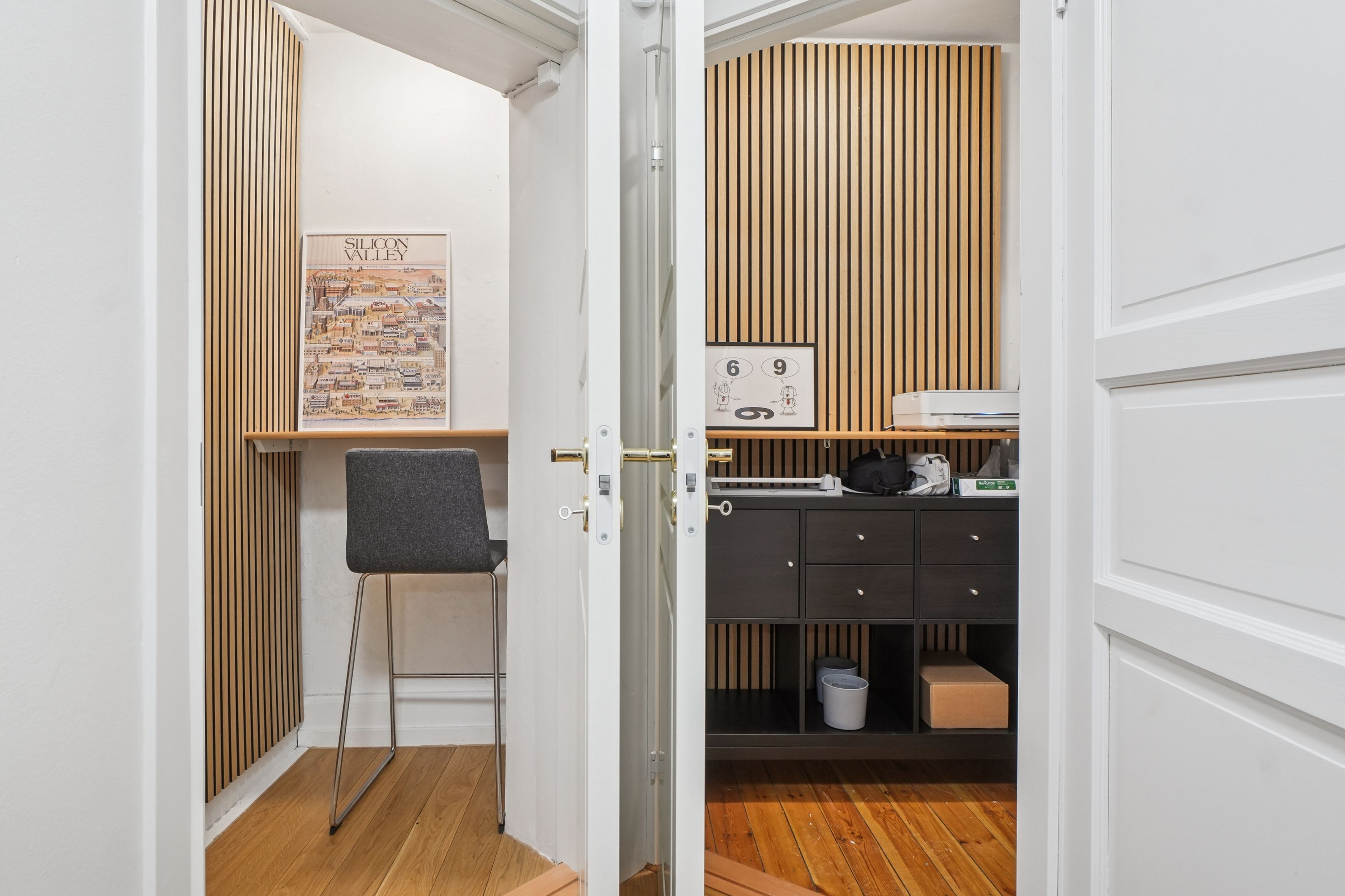 Åbne døre med indgang til et lille kontor med skrivebord, stol, hylde og et kalenderskildt med tallet 9