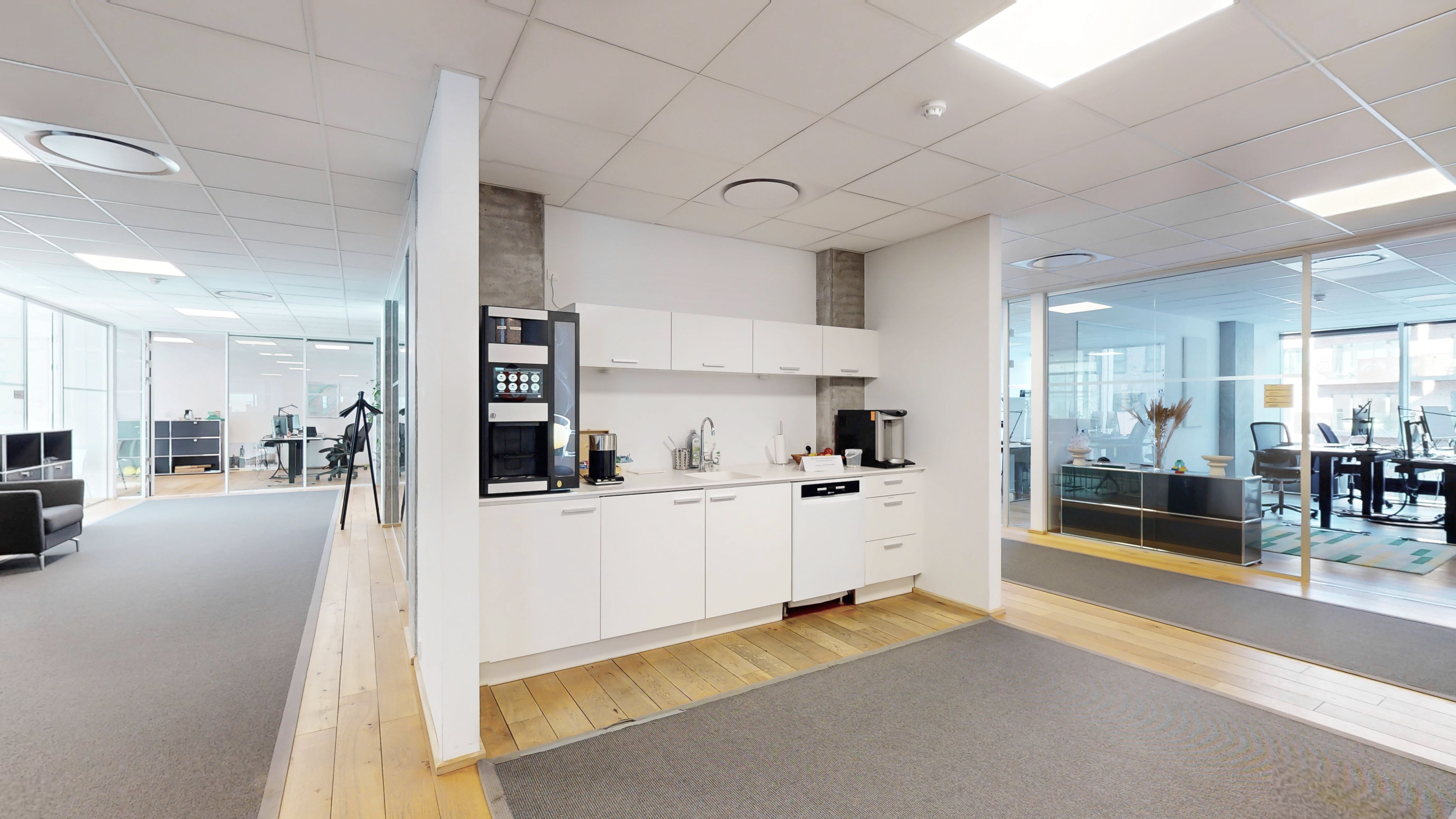 Moderne, glasfyldte vægge og høje lofter udgør dette kontorlokal. Komplet med en skandinavisk interiørstil og en simpel møbleret køkkenafdeling.