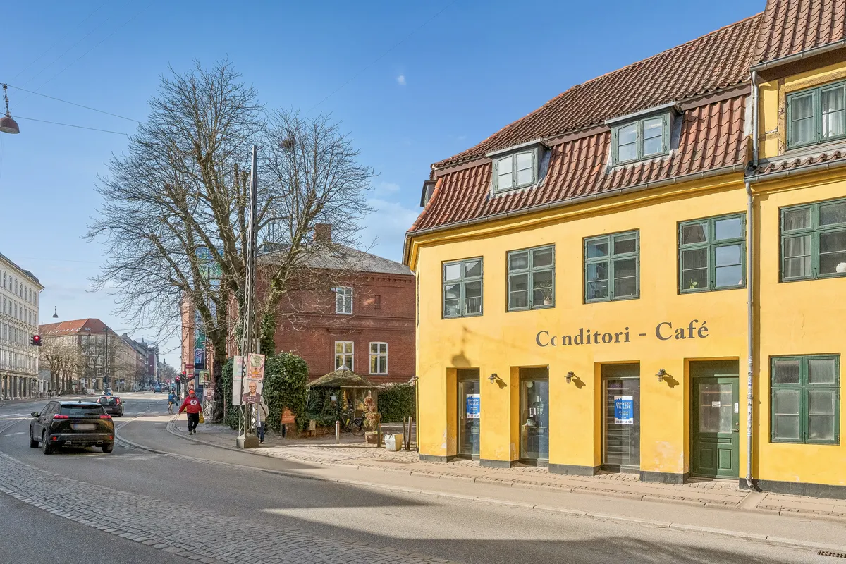 Café Cønditori på Vesterbrogade, København V, med gul facade og grønne ruder og døre, krydsningspunkt med biler, cyklister og trafiklys
