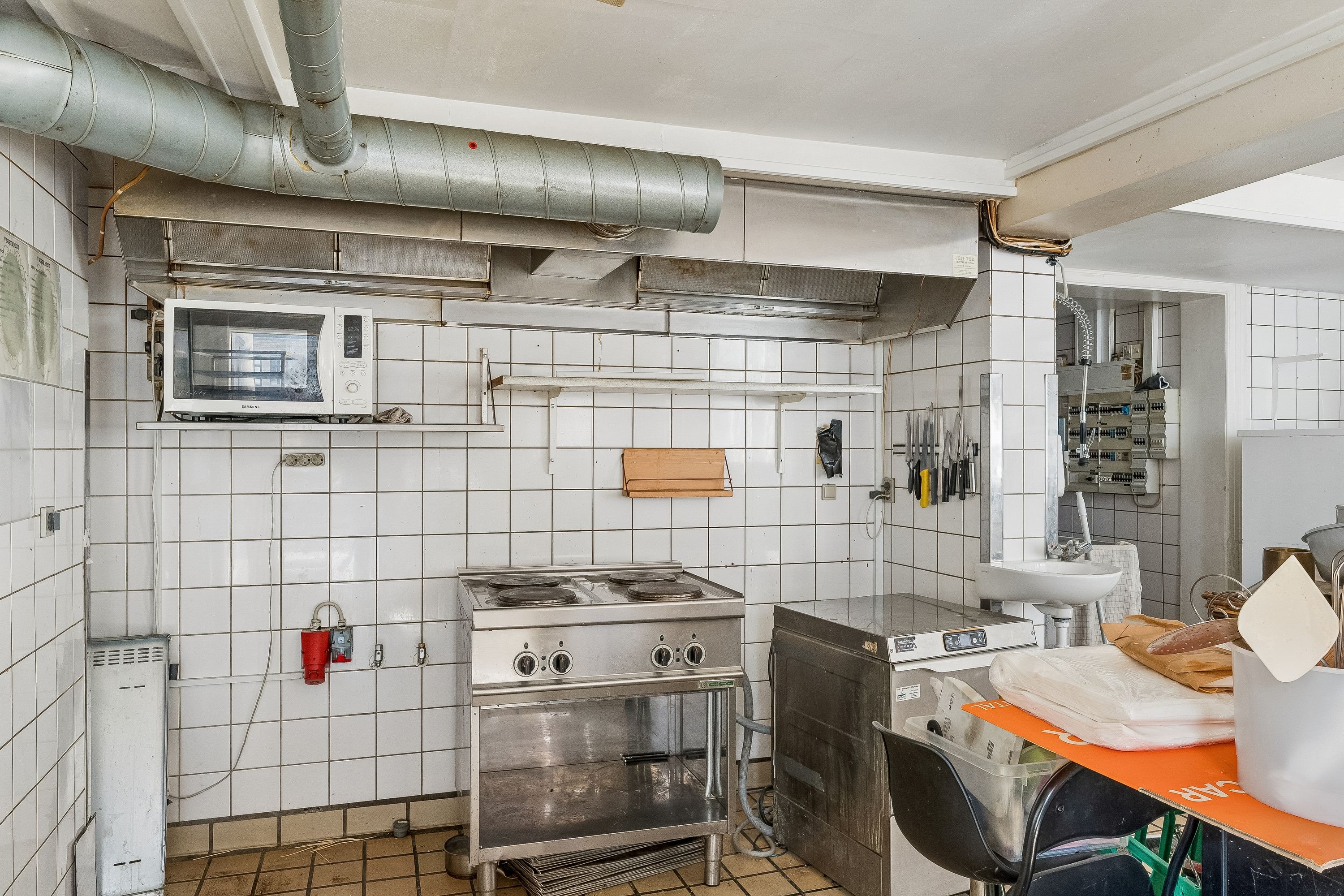 Et lille køkken med elektrisk komfur, komfurplade, mikrobølgeovn og køleskab, der er udstyret med alle nødvendige kogeudstyr