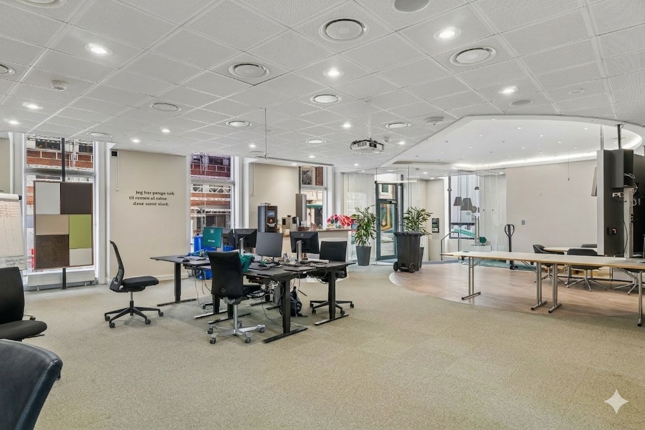 Kontor med moderne møbler og skriveborde, computere og plantepotter samt skriveborde og stolpe.