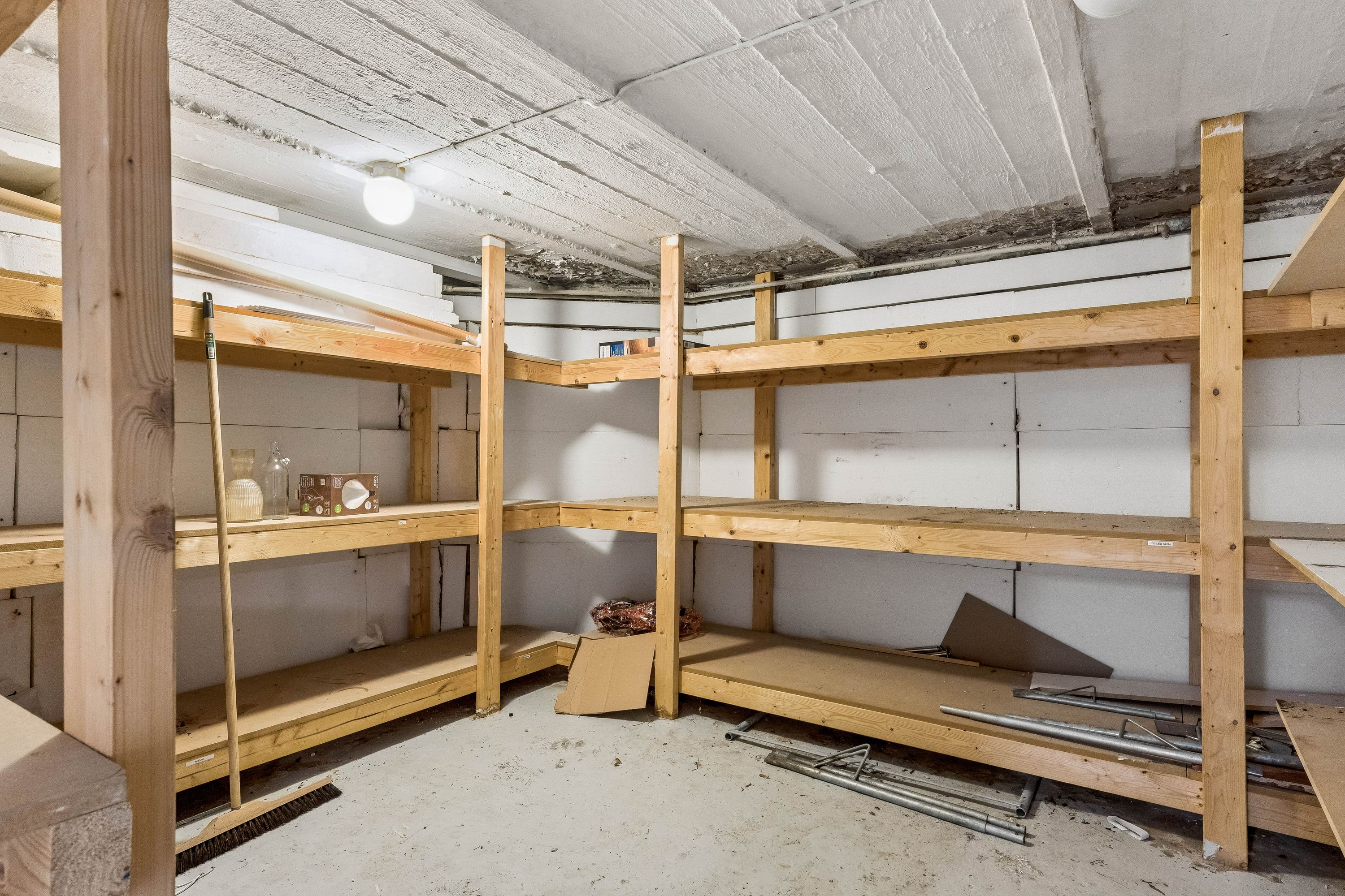 En møbleret lagerrum med lyse og rummelige hylder og en børste i siden