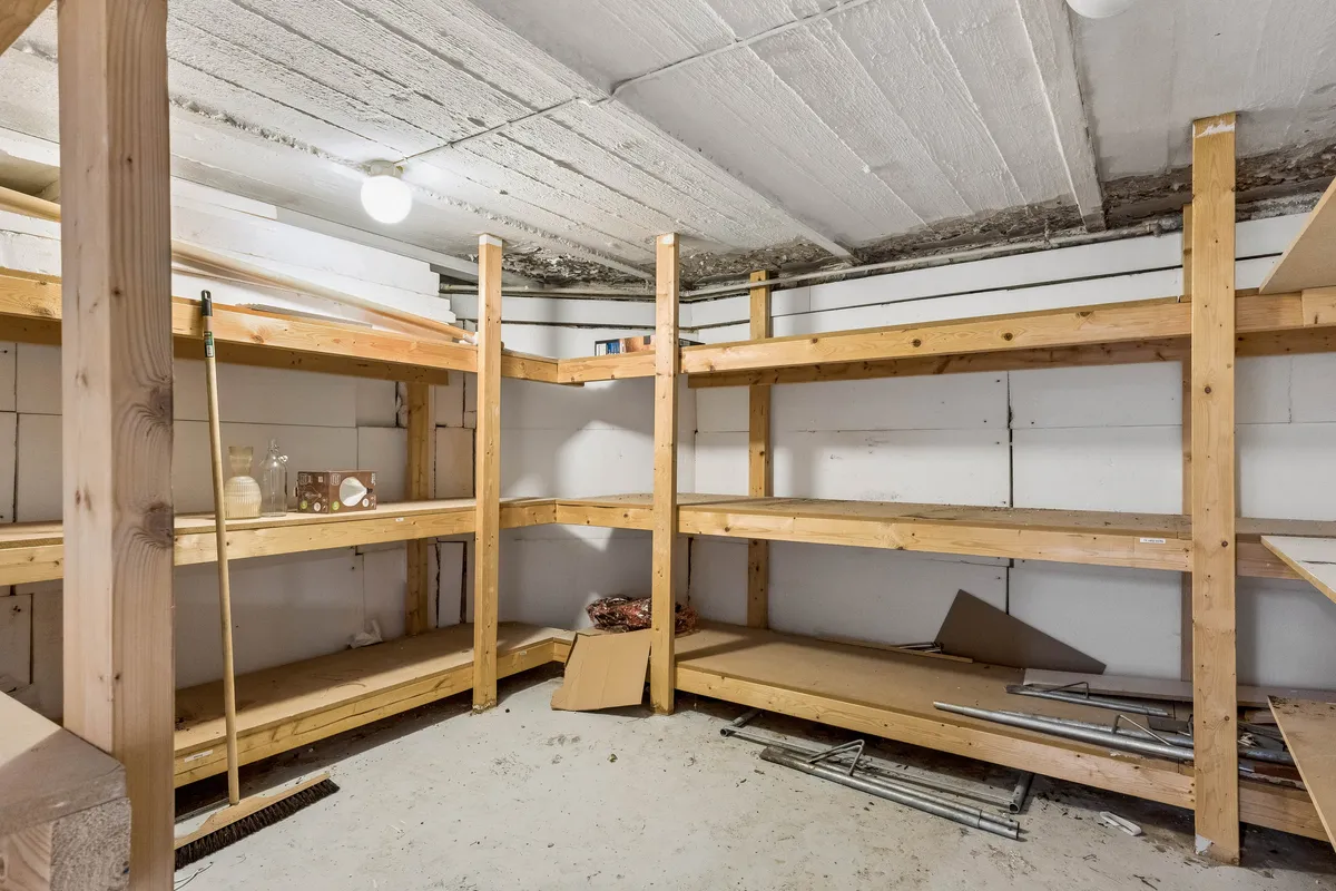 En møbleret lagerrum med lyse og rummelige hylder og en børste i siden