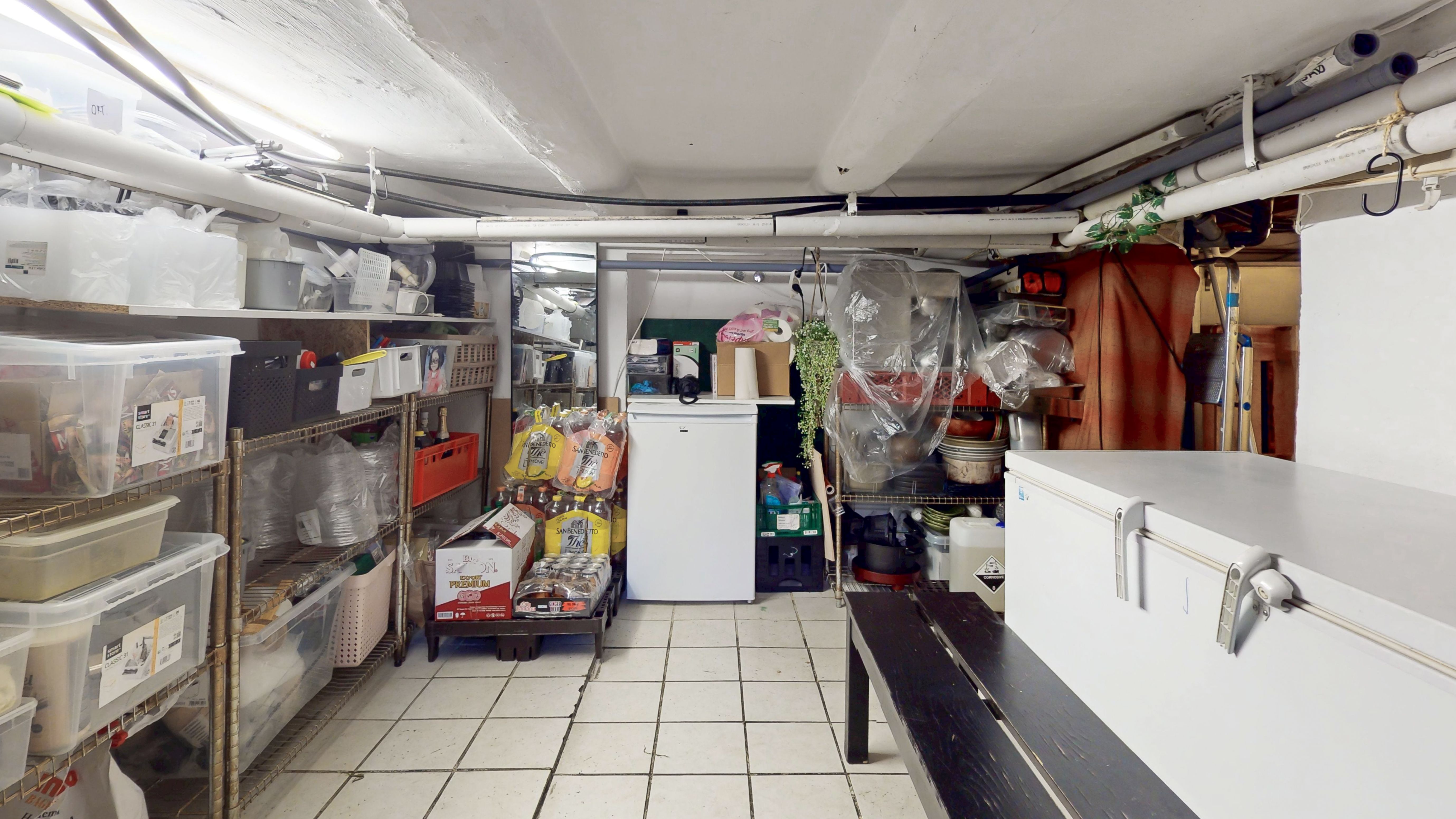 En stor lagerrum med højt gulv og højt til loftet. Rummet er fuldt med forskellige kassetyper, plastposer og andre lagerartikler.