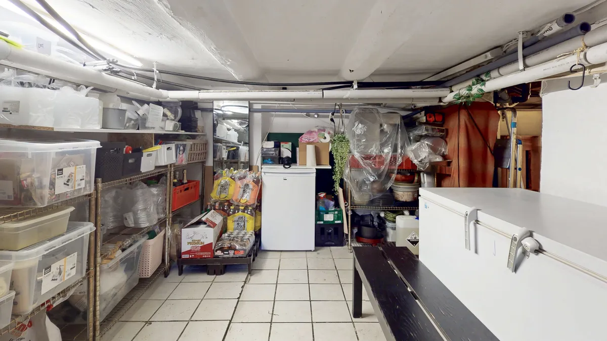 En stor lagerrum med højt gulv og højt til loftet. Rummet er fuldt med forskellige kassetyper, plastposer og andre lagerartikler.