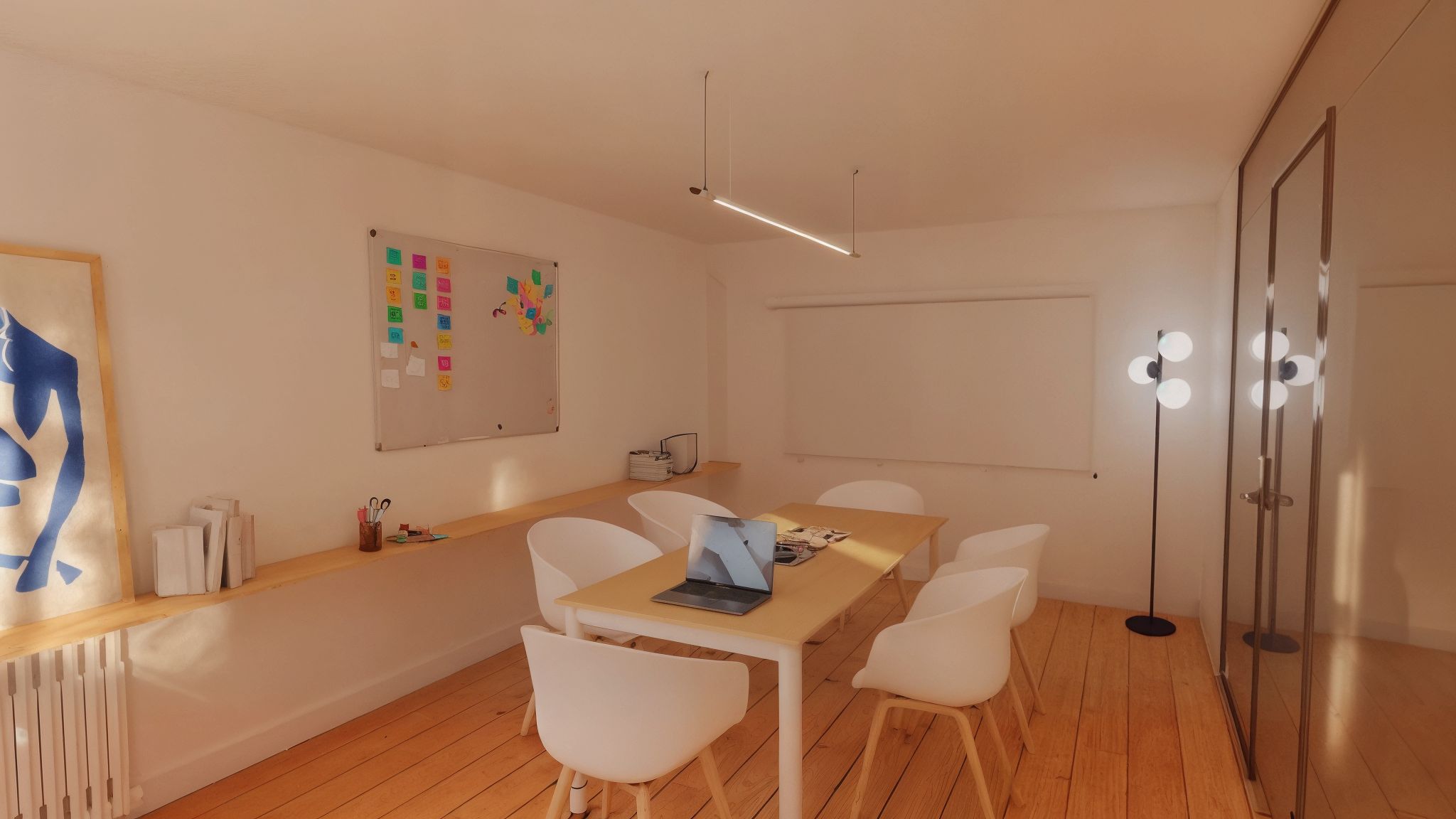 Et kontorlokale med lyse vægge og trægulv. Væggen er dækket af en magnetbord med post-it noter. Et skrivebord med computer og briller og en lampe.