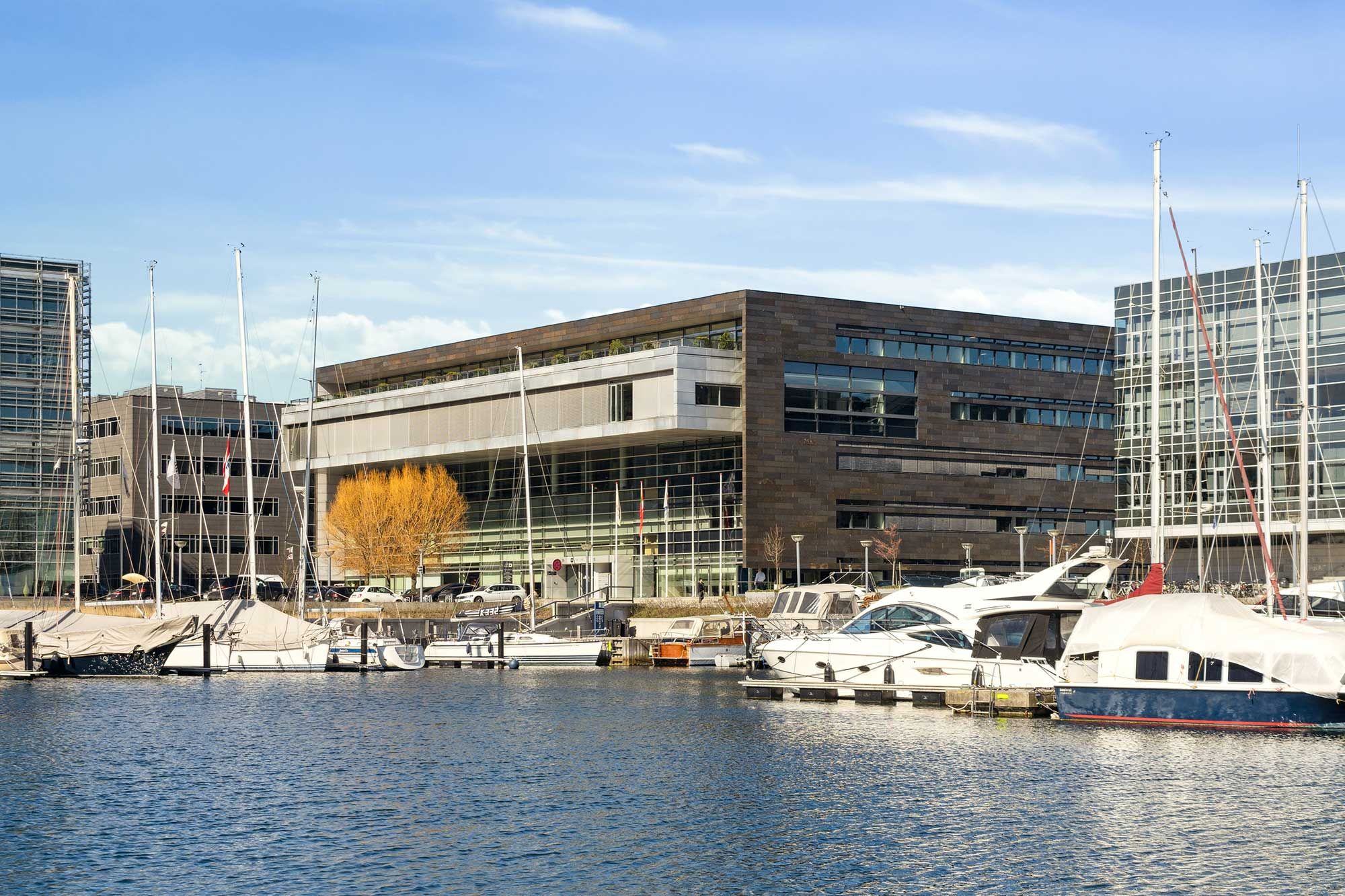 Markant The Cube bygning med udsigt over Øresund og havn med parkerede biler og ankerede både