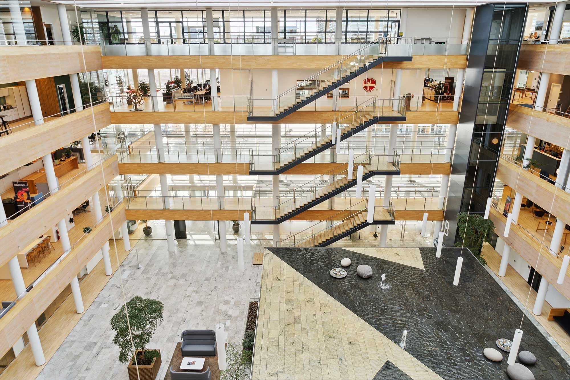 et glas og træloftet atrium i et moderne og stort kontorbygning med udsigt over Øresund og Tuborg Havn