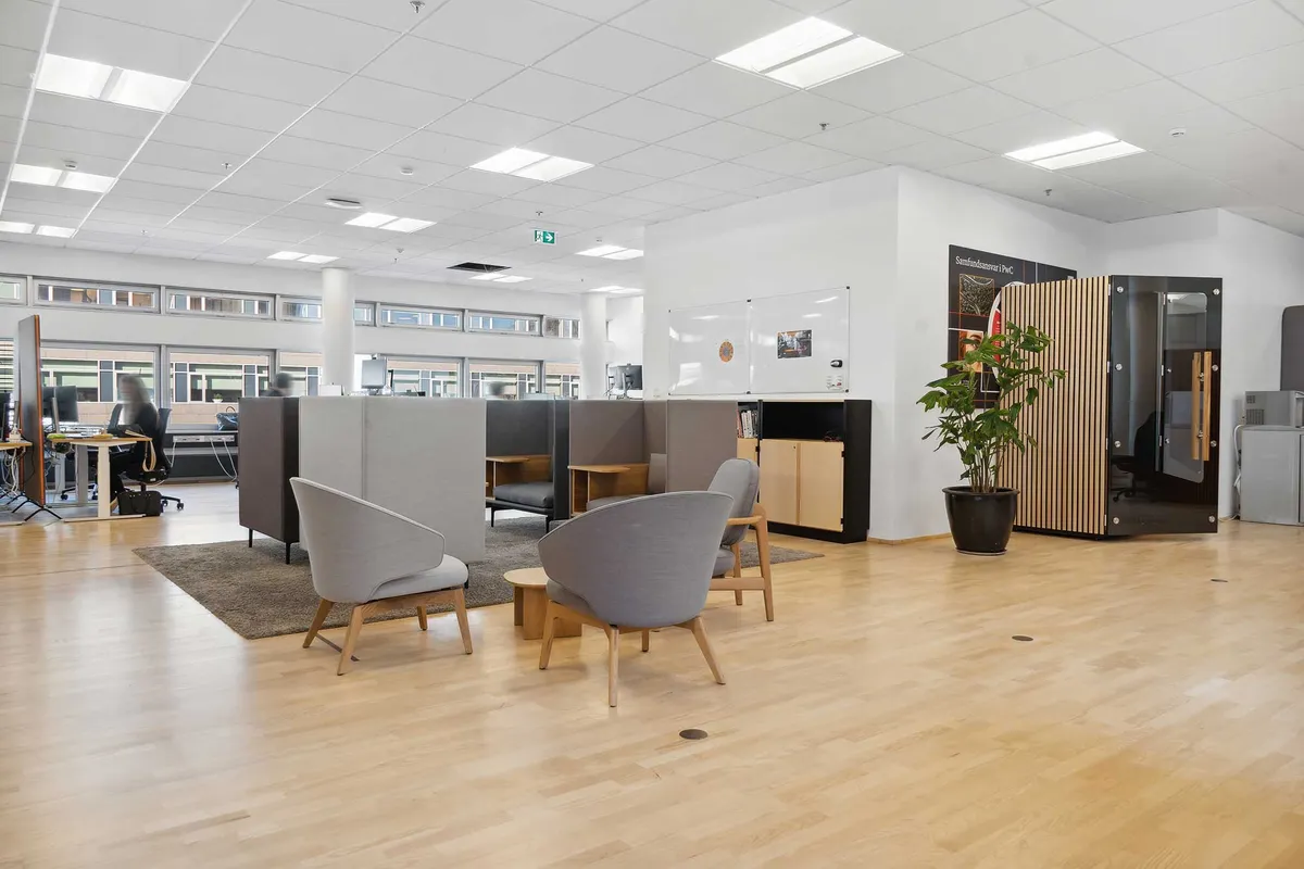 Kontor i Tuborg Nord med lyse loftslamper, moderne møbler, bord og stole, plante, skrivebord, skrivebordslys og vinduer med udsigt over Øresund og Tuborg Havn