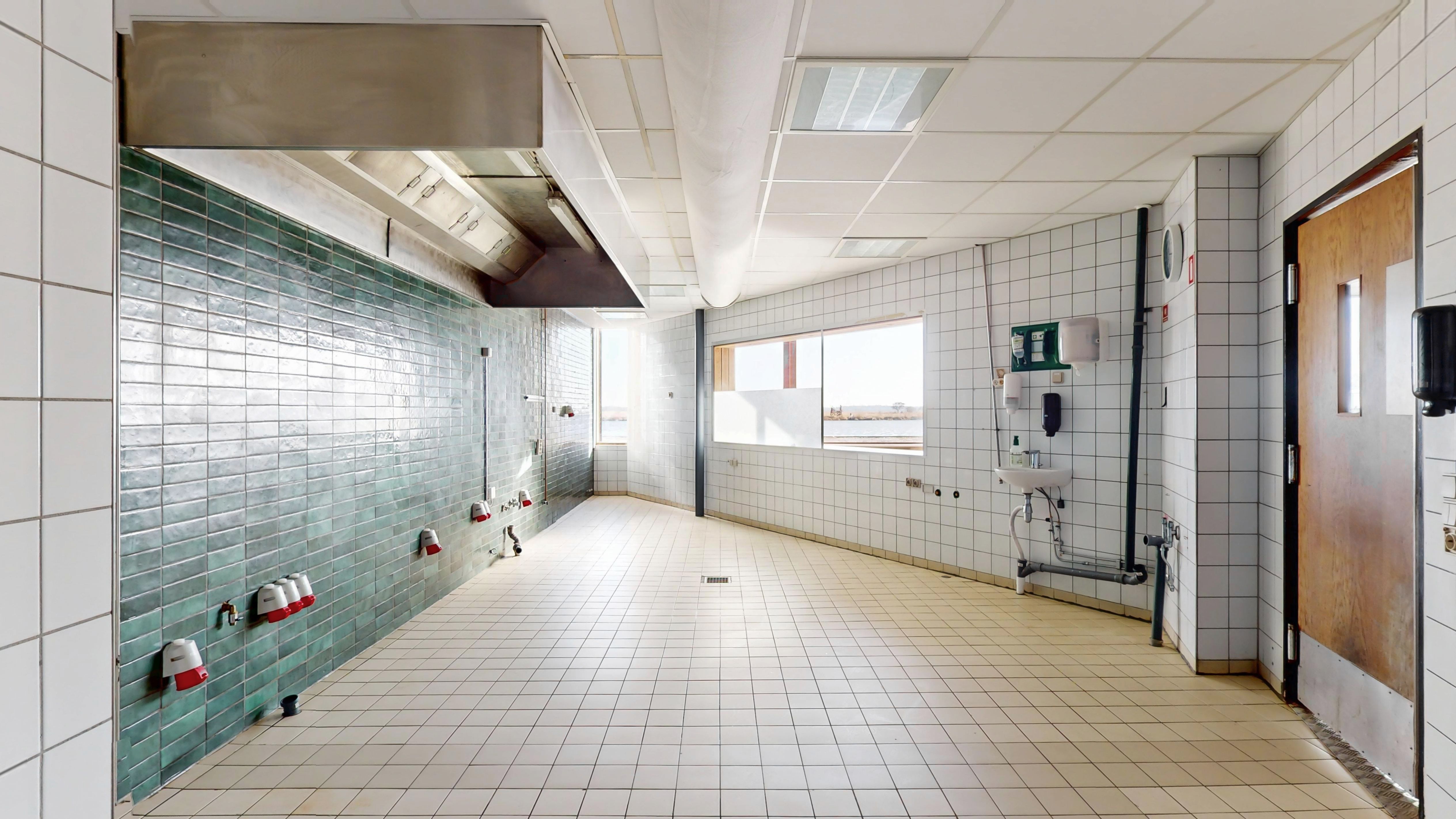 Moderne køkken med hvide kakel og møbler samt grønne glaskakel og metalliske ventiler og røgaffugter i loftet