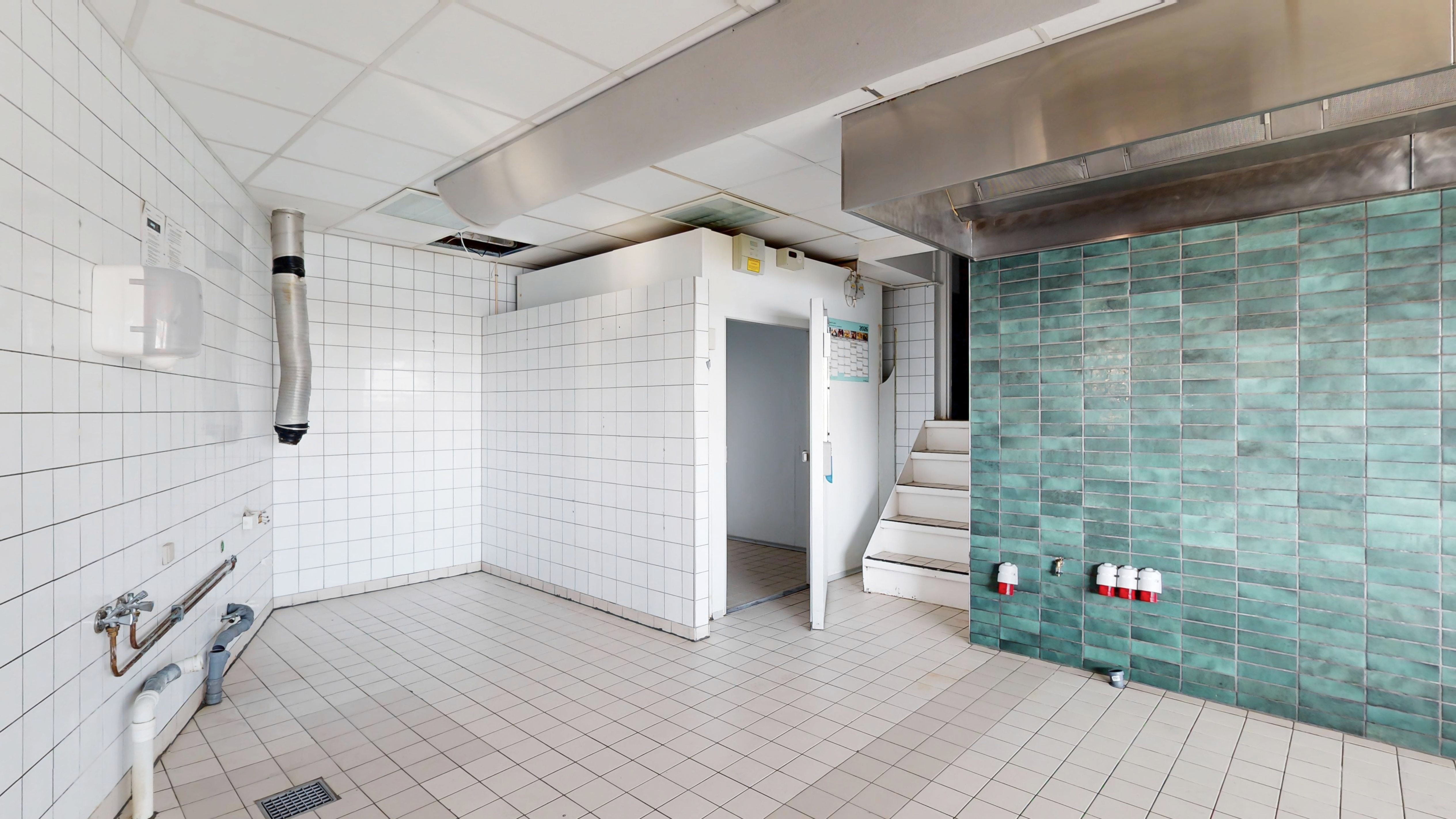 Hvid og turkis keramik udgør gulvet og væggene i et moderne rum med stålloft og trappe op til et øvre rum