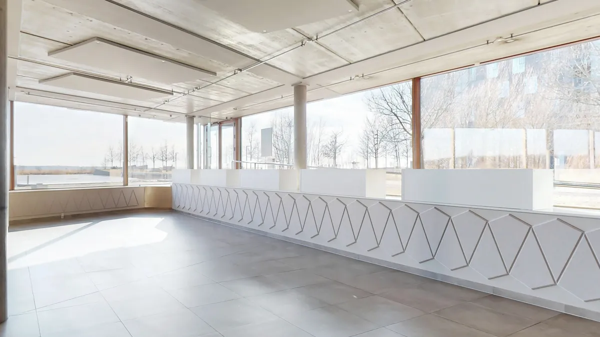 Store, lyse vinduer med udsigt til skov og vand i baggrunden. Moderne, hvidt gulv og vægge. Minimalistisk og stilren indretning med rektangulært design