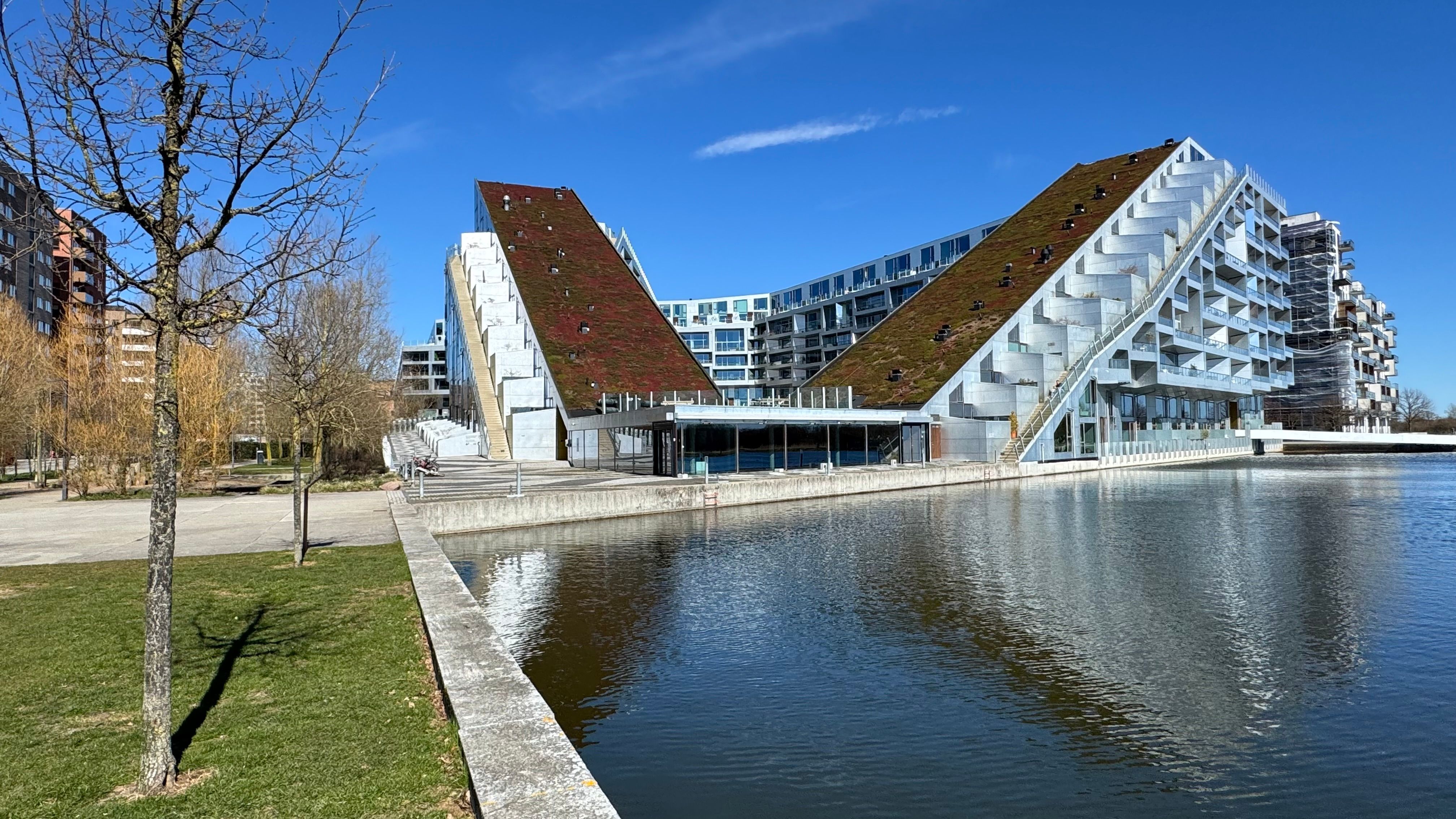 Moderne bygning med grønne tagterrasser og vand i Ørestad. Bygningens lyse facader og grønne tag er særligt attraktive og giver et flot udseende