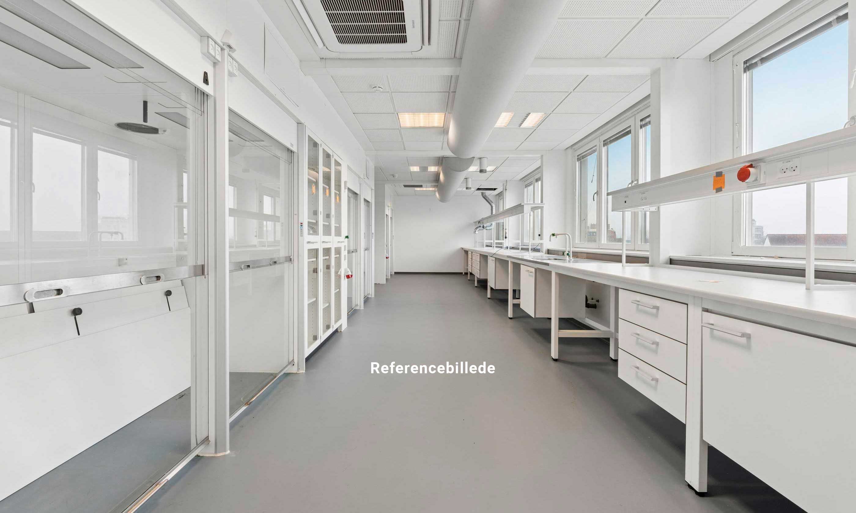 Lyst laboratorium med glasvægge og hvide arbejdsborde. Værelse med lyse gulve og moderne klimaanlæg. Vindue med solskærm og elektriske stik.