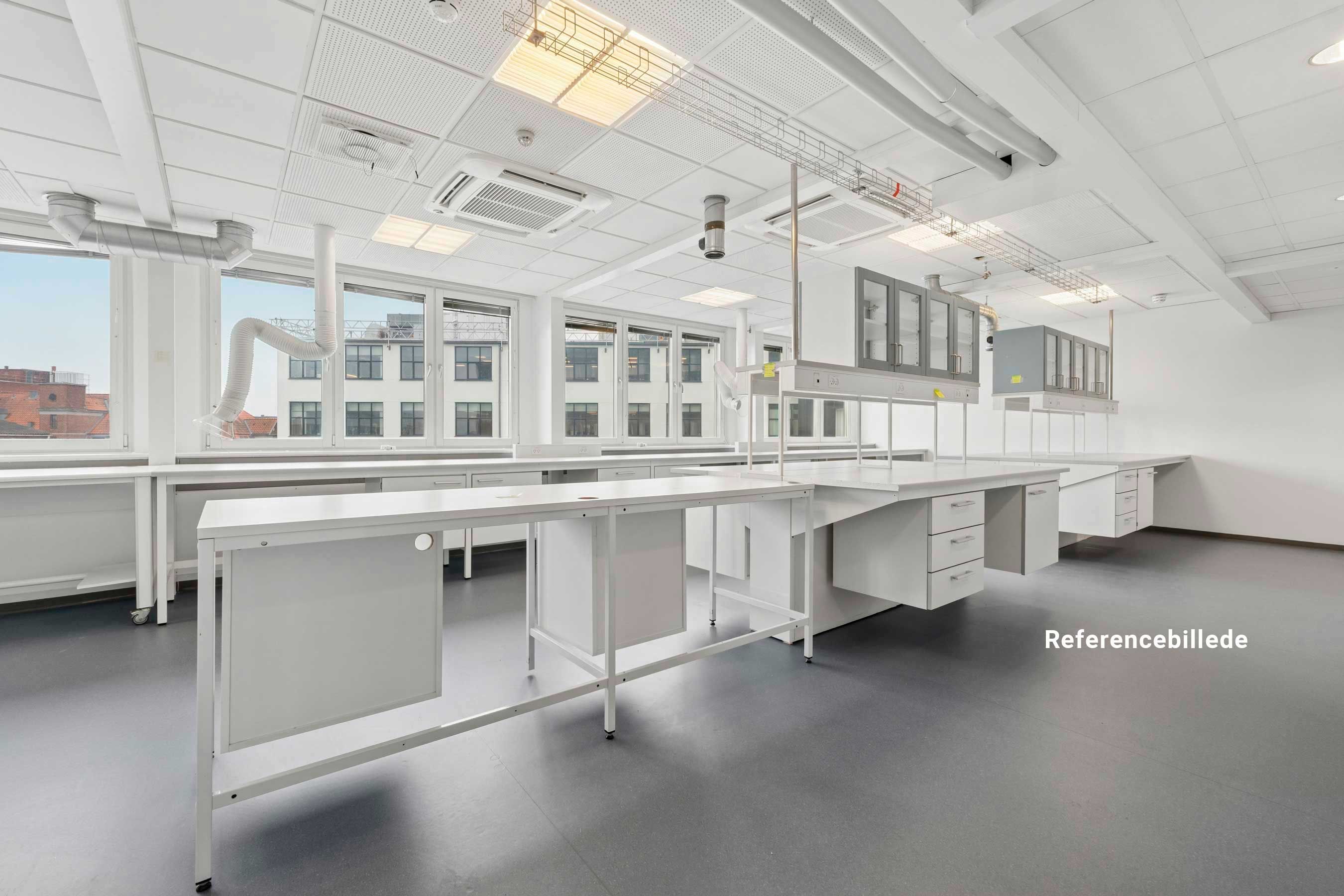 Referencebillede af nyt laboratorie med hvide skriveborde, ventiler og vinduer med udsigt til bygninger