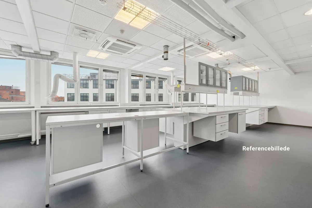 Referencebillede af nyt laboratorie med hvide skriveborde, ventiler og vinduer med udsigt til bygninger