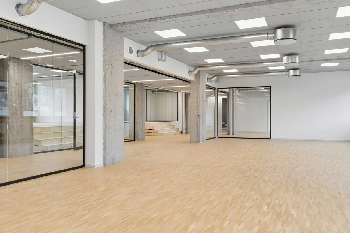 Et stort, lyse og lyst kontor med højt til loftet og masser af glas og træ. Værelserne er moderne indrettet og har højkvalitets gulvbelægning.