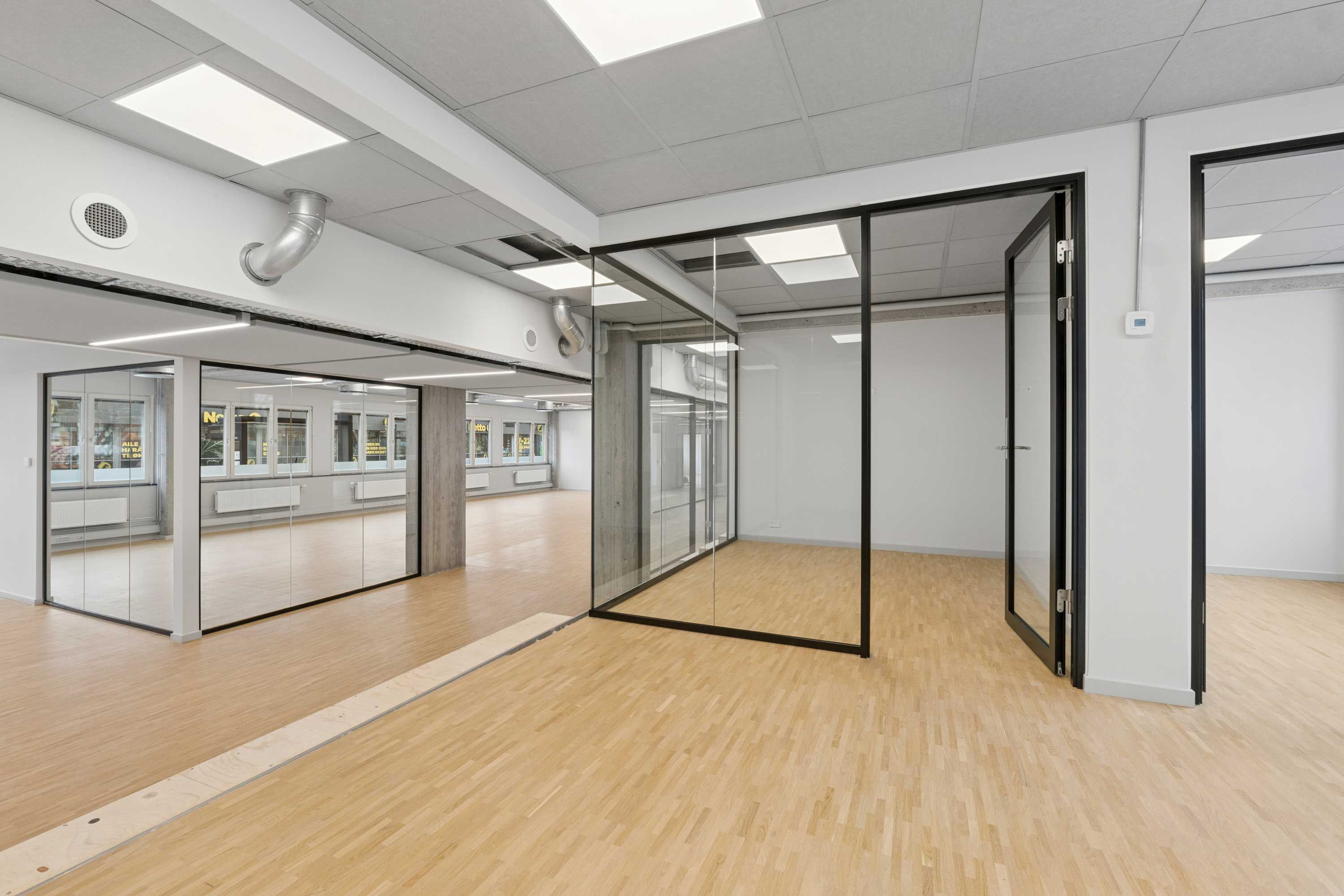 Hvidt lokale med højloft og glasvægge. Efterlad en kommentar til lokalet. Luftkanaler og ventilationshætte er installeret i loftet. Væggene og gulvet er lavet af træ