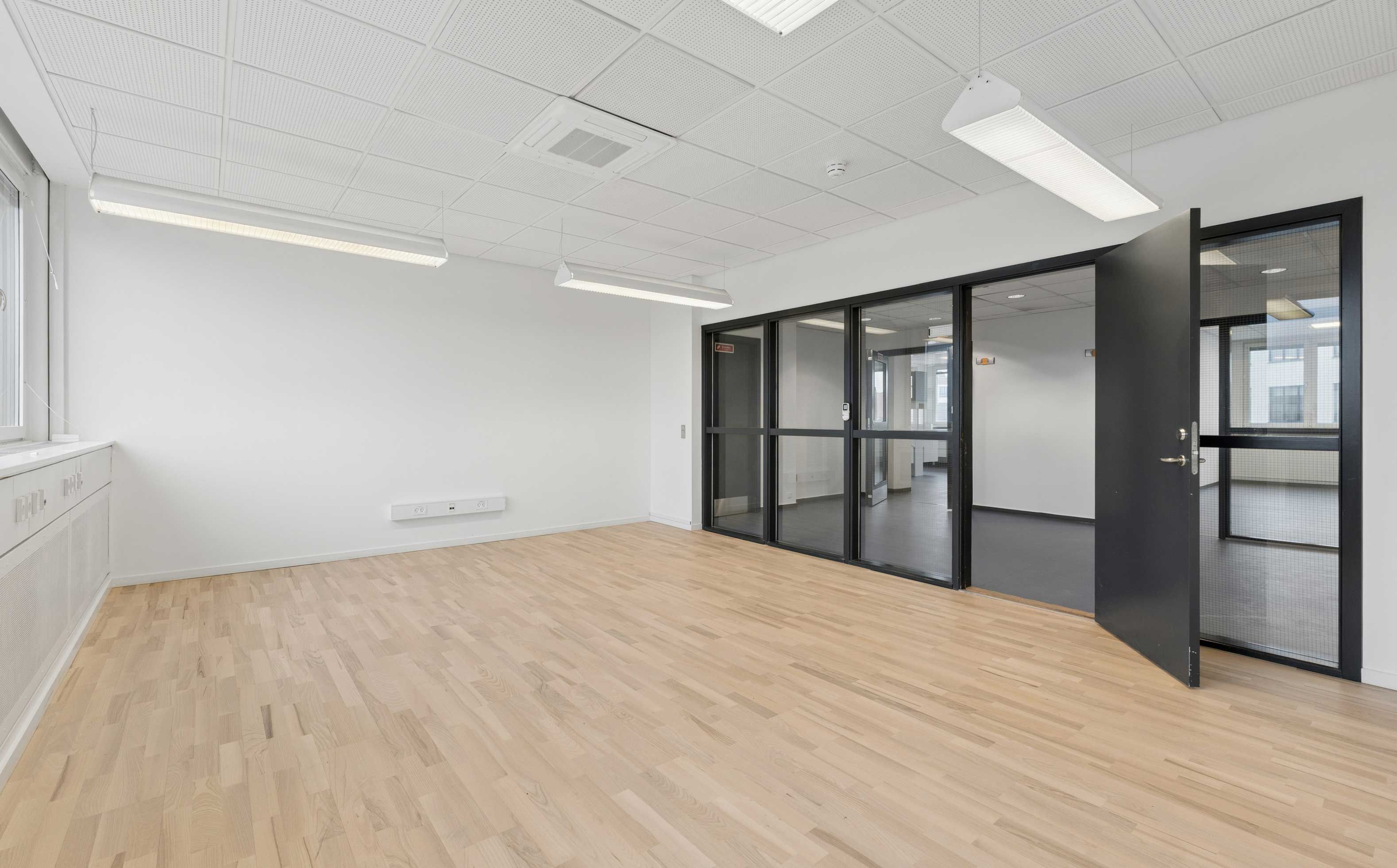 Hvidt og glas med åben dør og slanke møbler i moderne kontor med højloft og lysekroner