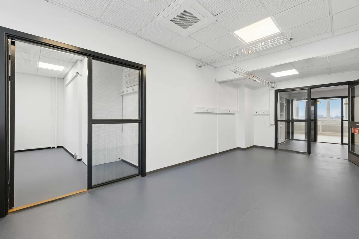 Et moderne laboratorium med lyse gulve og hvide vægge samt store glasruder og glasdøre, som giver god belysning og udsigt til byen