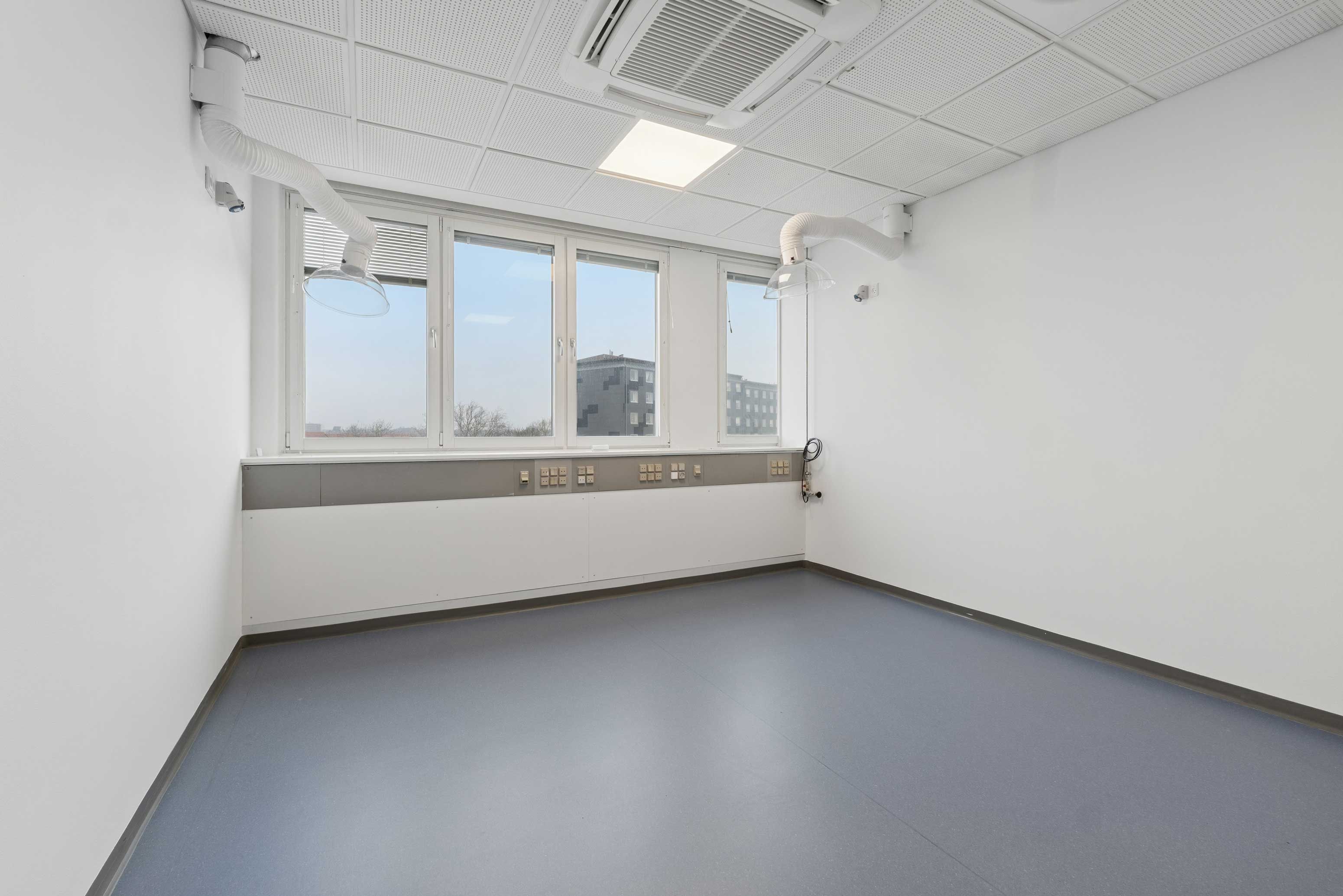 Lyst og moderne laboratorium med kontor, store vinduer, lyse loftsbrædder og lysegule gulve. Moderne belysning og industristil.