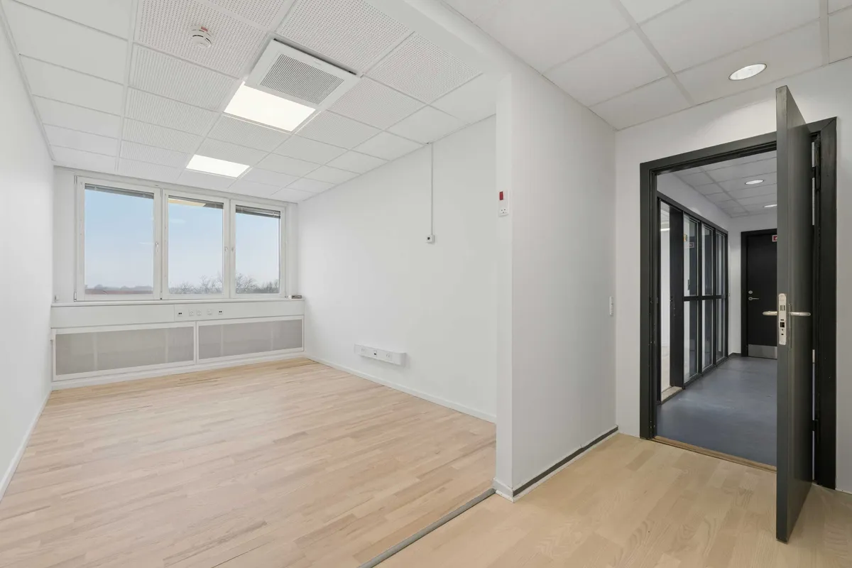 Moderne laboratorium med hvidt loft og lysegult gulv og hvide vægge med store vinduer. Sorte døre og hvide vægpaneler.