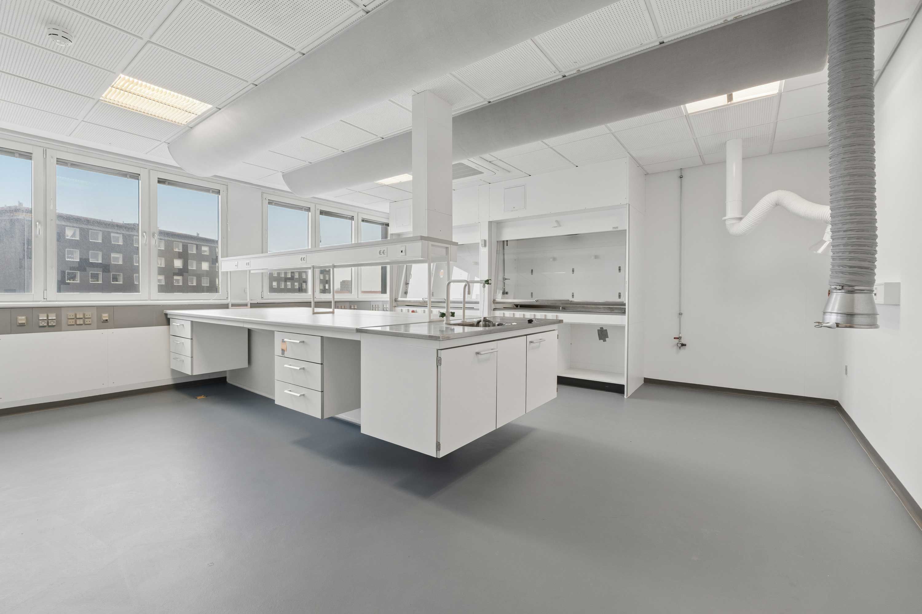 Lyst og moderne laboratorium med højt loft, ren gulv og store vinduer. Værelse med høj kvalitet og lysefarvede vægge.