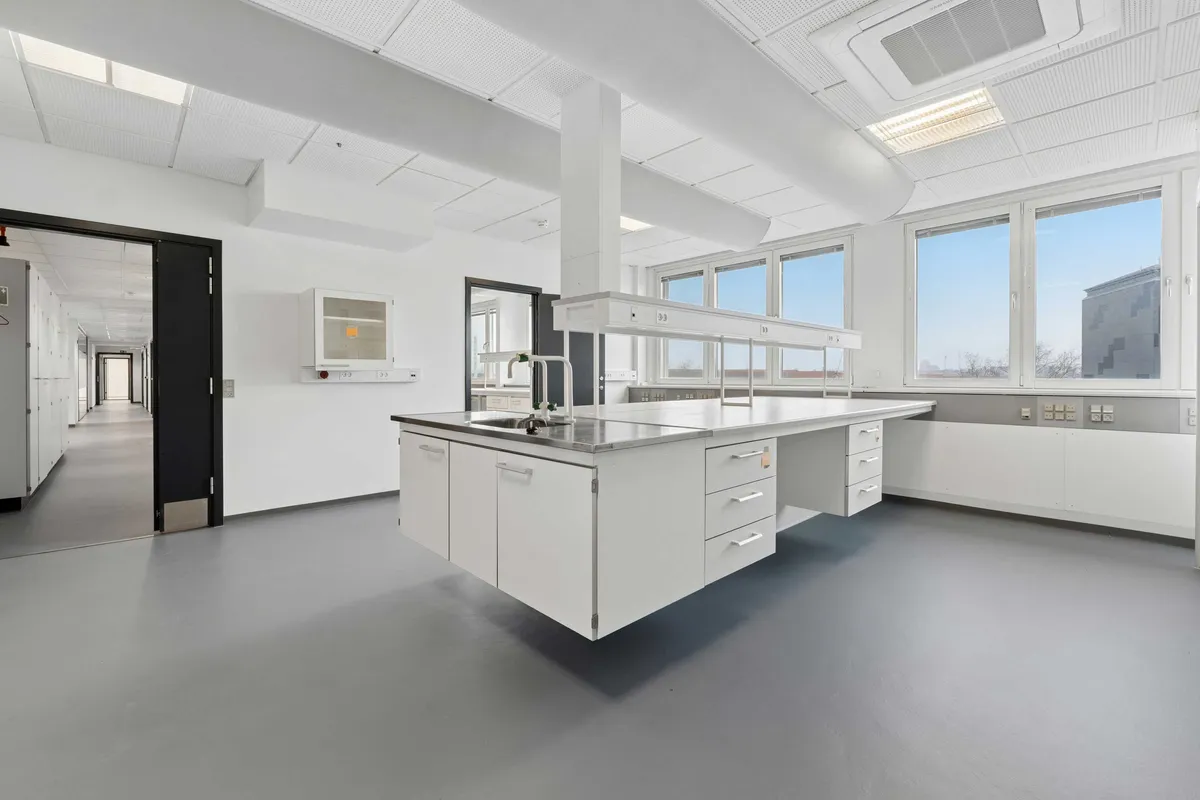 Lyst laboratorium med lyse lofter og højt til loftet, udstyret med flere højteknologiske apparater og lysevinduer, der sikrer godt lys og et åbent rum