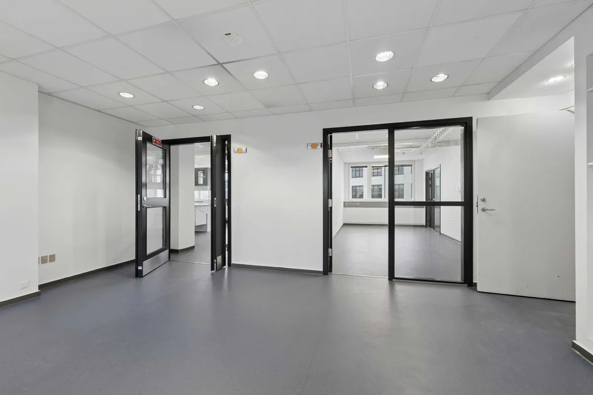 En lys, moderne laboratorie- og kontorbygning med glasdøre og hvide vægge. Det er en nyistandsat ejendom på Rønnegade 4 i København Ø.
