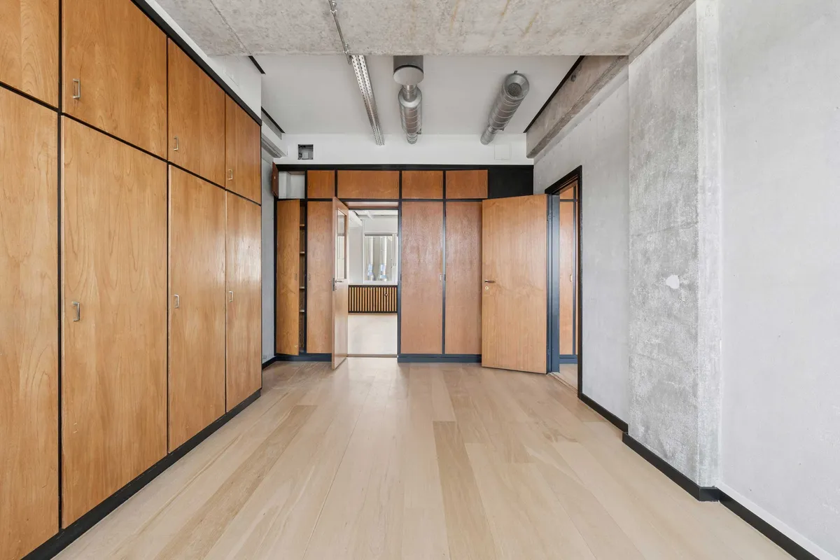 En lejlighed med lyse gulve, moderne indretning og store træskabe samt åbne døre og vinduer