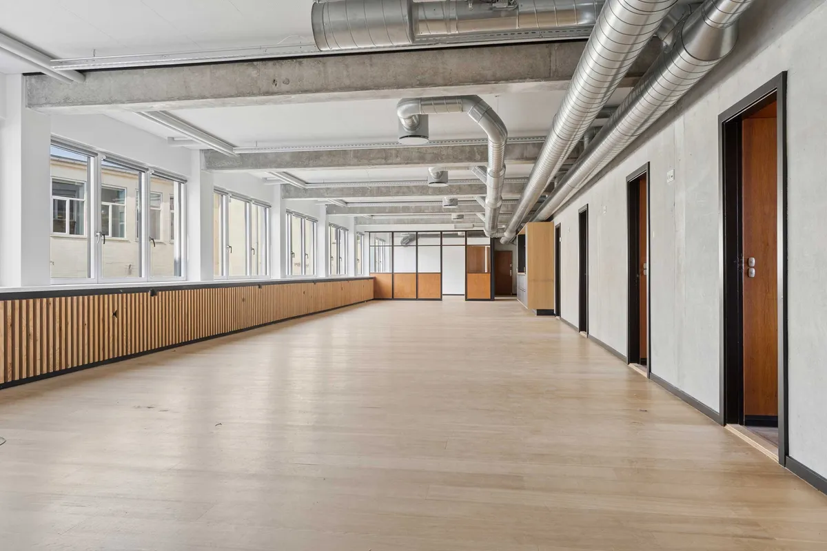 Kort og klar alt-tekst med relevante nøgleord om det, der er synligt på billedet: Åben indretning med hårdt trægulv og lyse lofter samt store vinduer og lysekroner